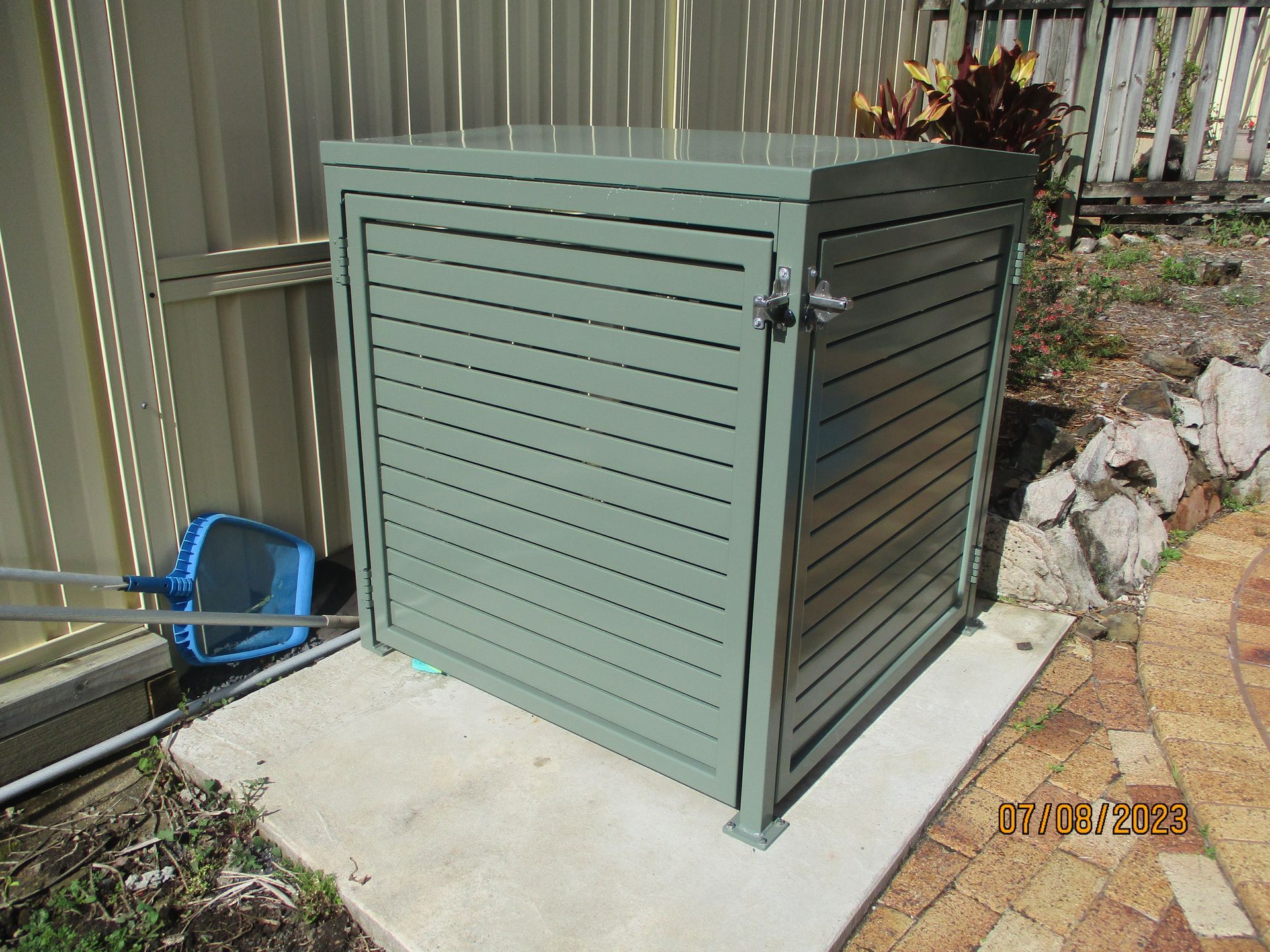 A green shed is sitting on a concrete surface next to a fence — Fabricator In Coffs Harbour, NSW