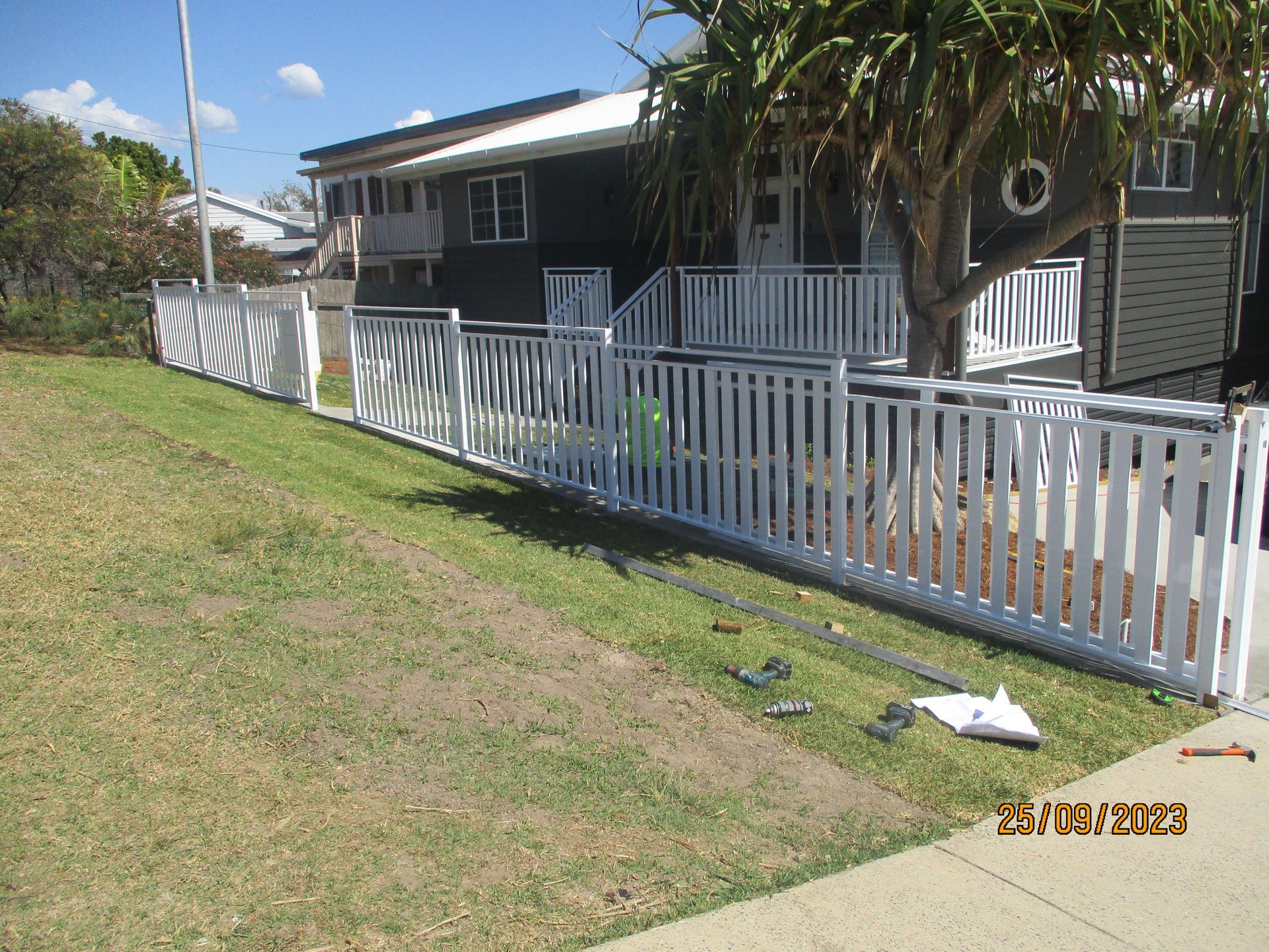 A white picket fence is in front of a house — Fabricator In Coffs Harbour, NSW