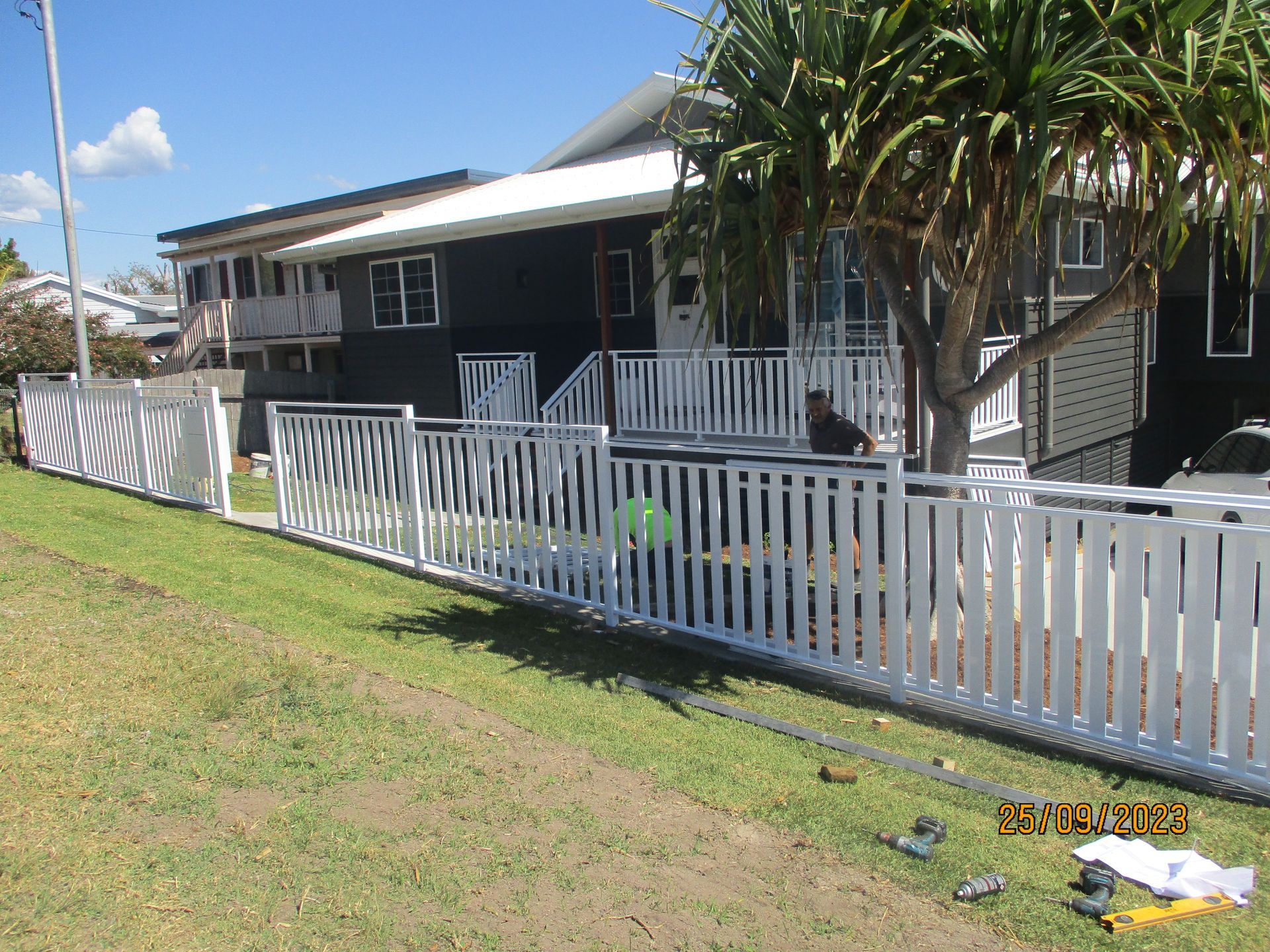 A white picket fence is in front of a house — Fabricator In Coffs Harbour, NSW