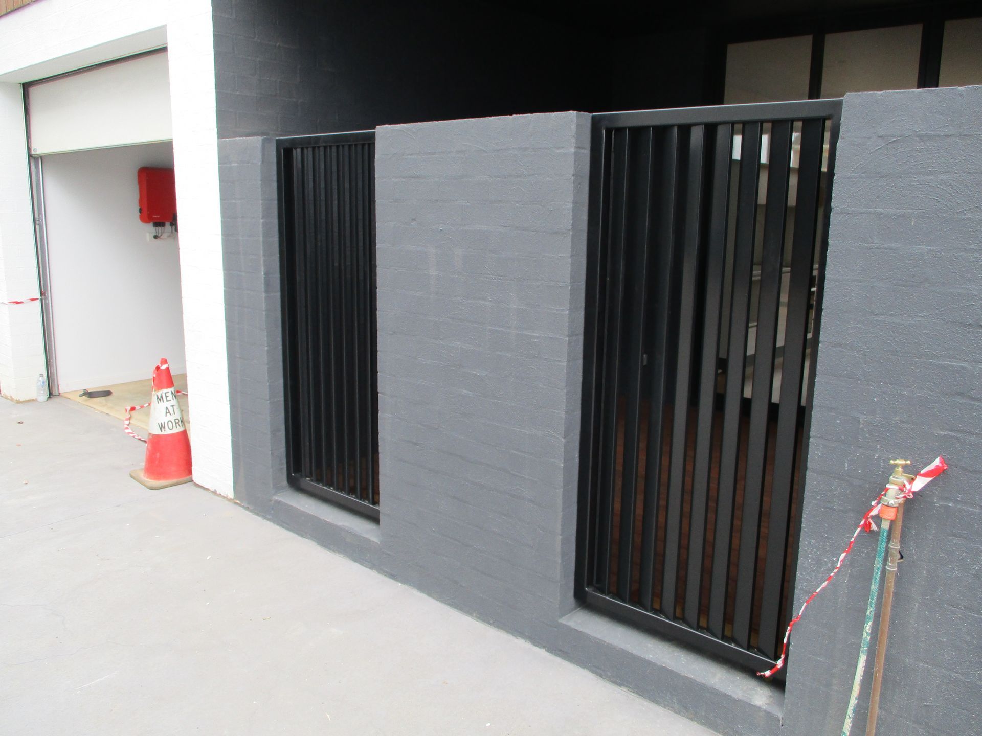 A black fence is surrounding a building with a red cone in the background — Fabricator In Coffs Harbour, NSW