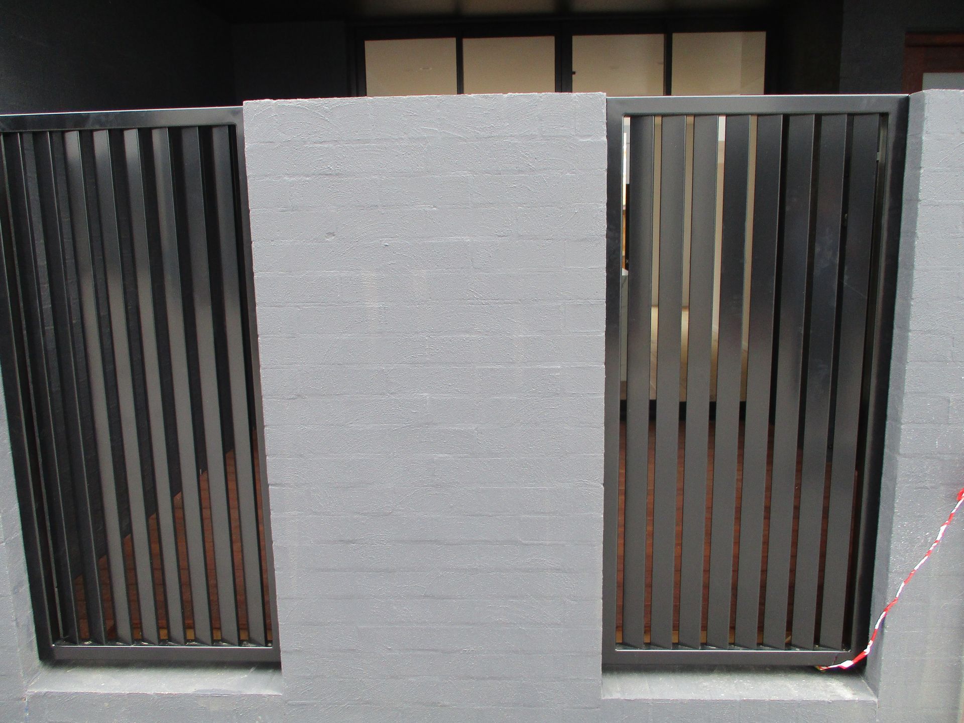 A gray brick wall with a black fence in front of it — Fabricator In Coffs Harbour, NSW