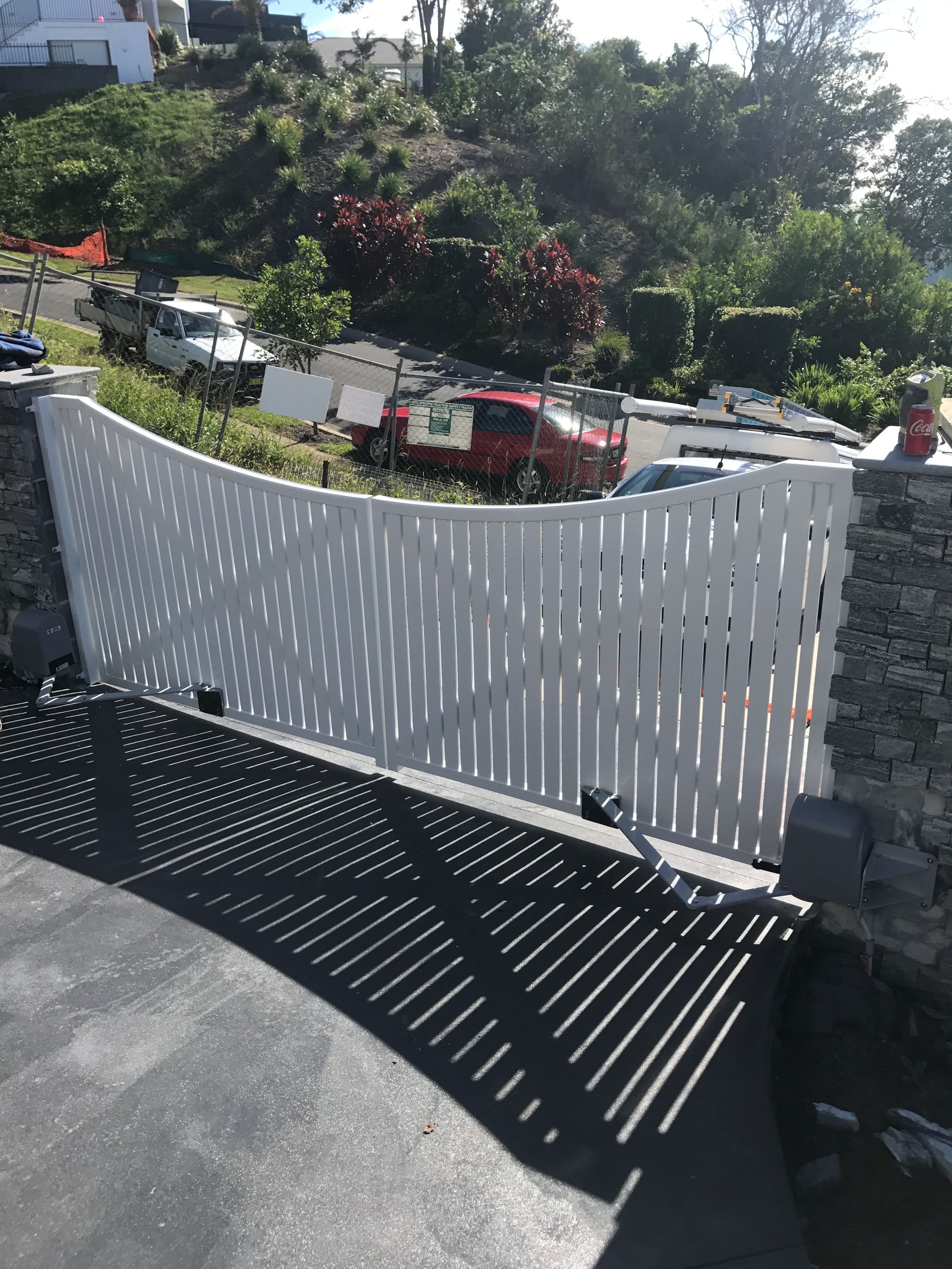 A white fence is surrounding a parking lot with cars parked behind it — Fabricator In Coffs Harbour, NSW