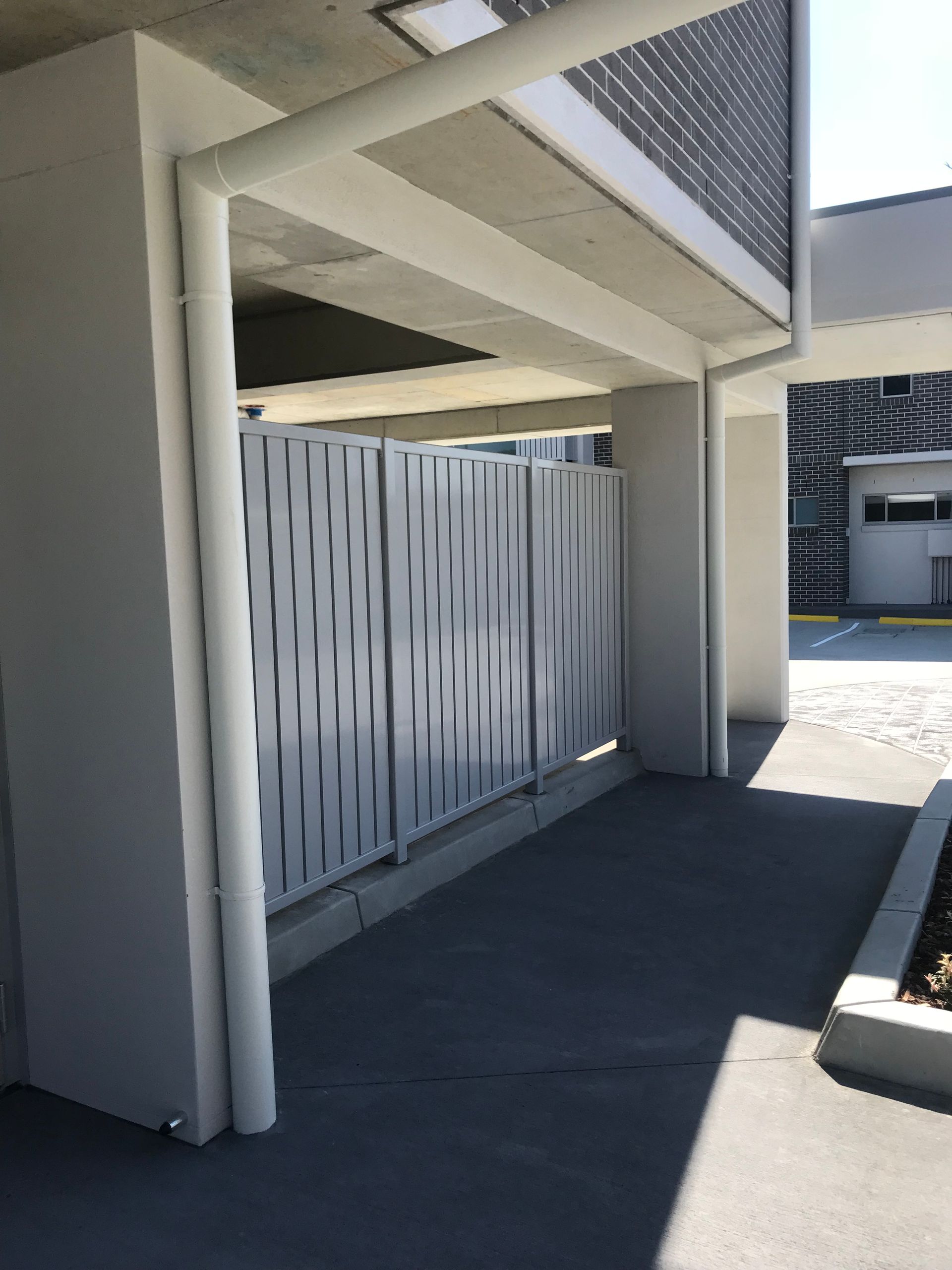 A white fence is surrounding a building with a drain pipe — Fabricator In Coffs Harbour, NSW