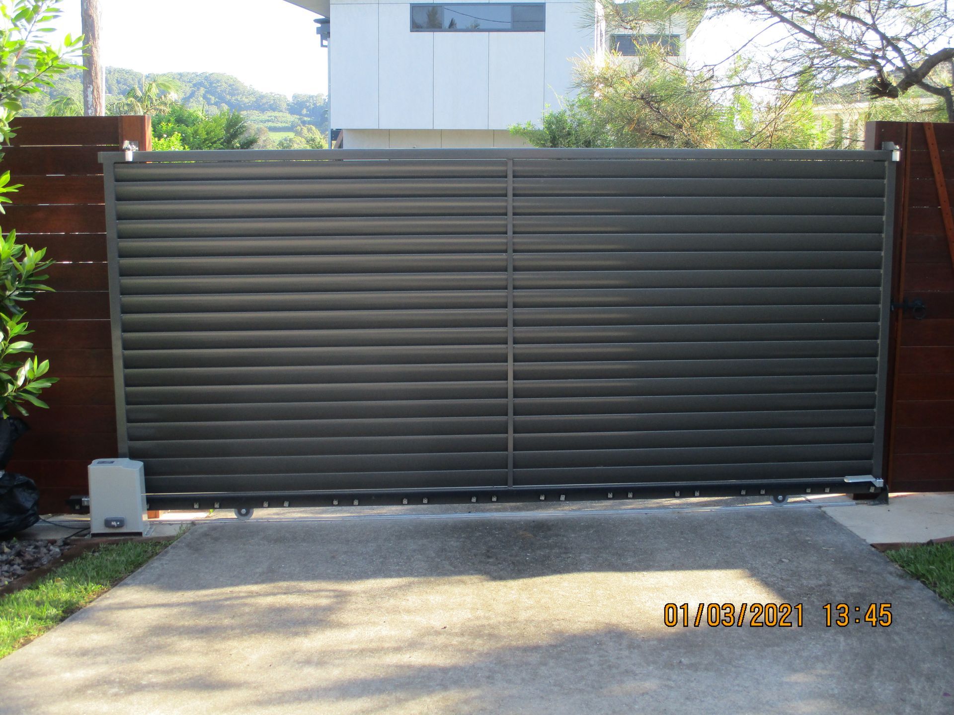 A sliding gate is open to a driveway in front of a house — Fabricator In Coffs Harbour, NSW