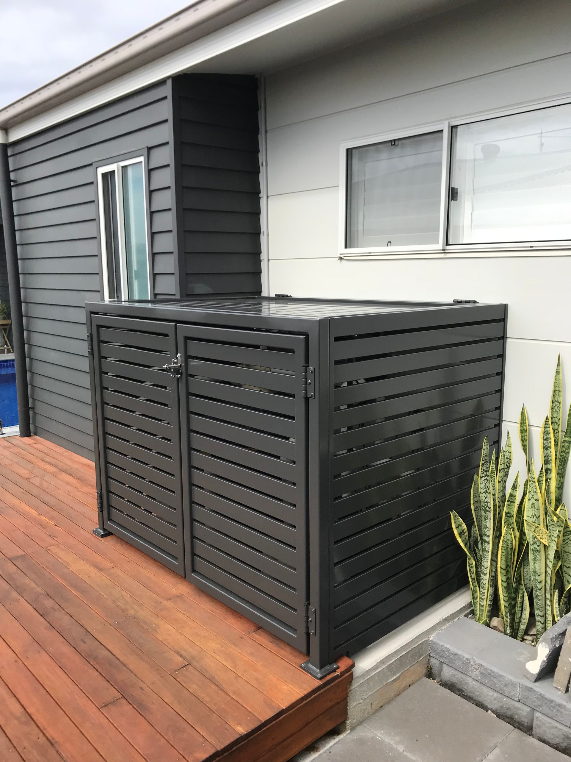 A black fence is sitting on the side of a house next to a wooden deck — Fabricator In Coffs Harbour, NSW