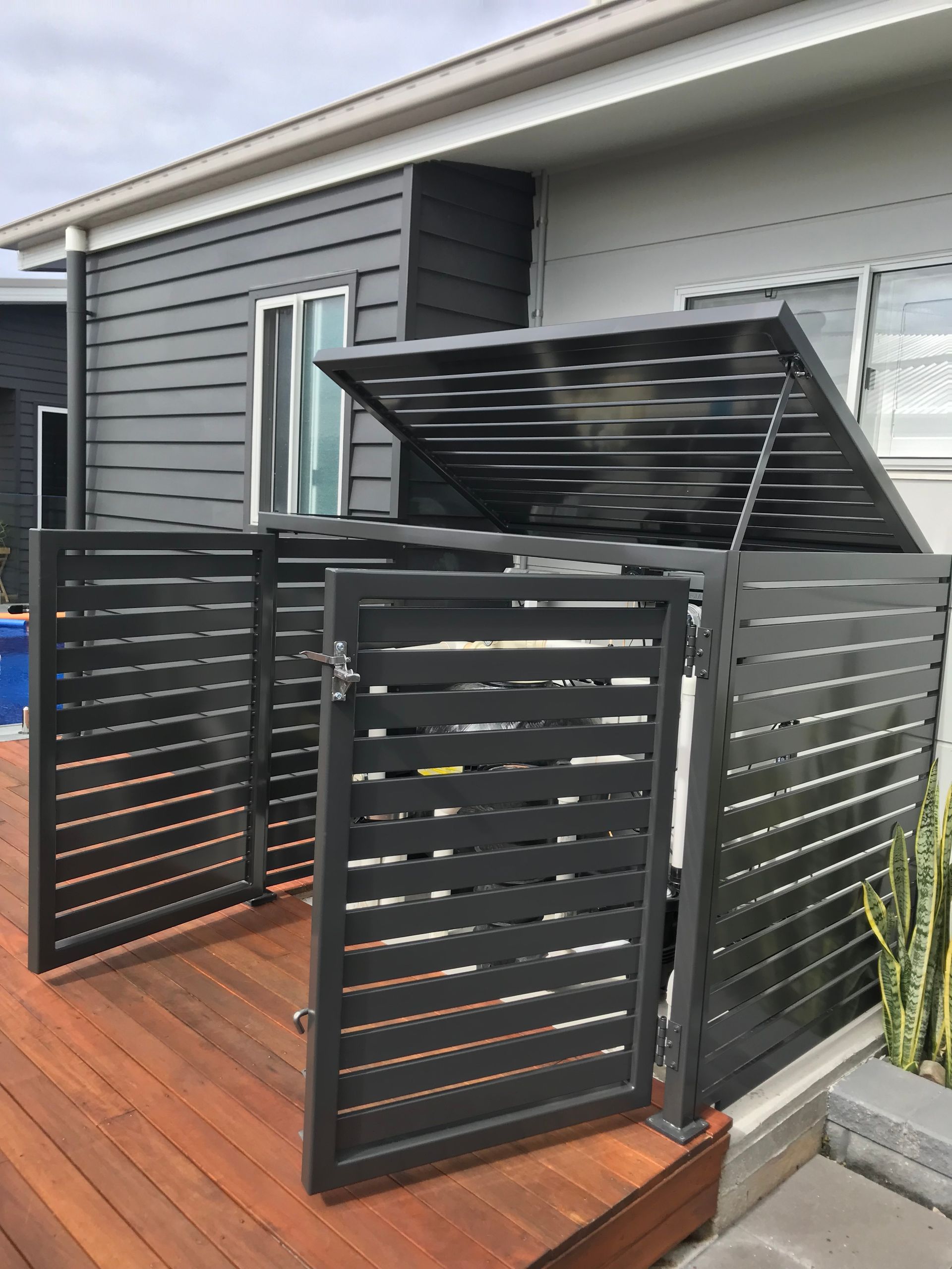 A black trash can is sitting on a wooden deck next to a house — Fabricator In Coffs Harbour, NSW