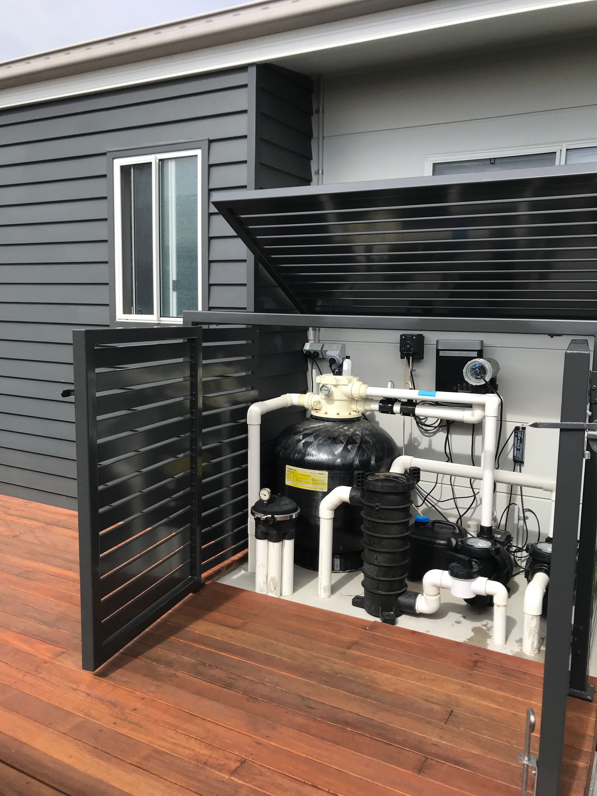 A pool pump is sitting under a fence on a wooden deck — Fabricator In Coffs Harbour, NSW