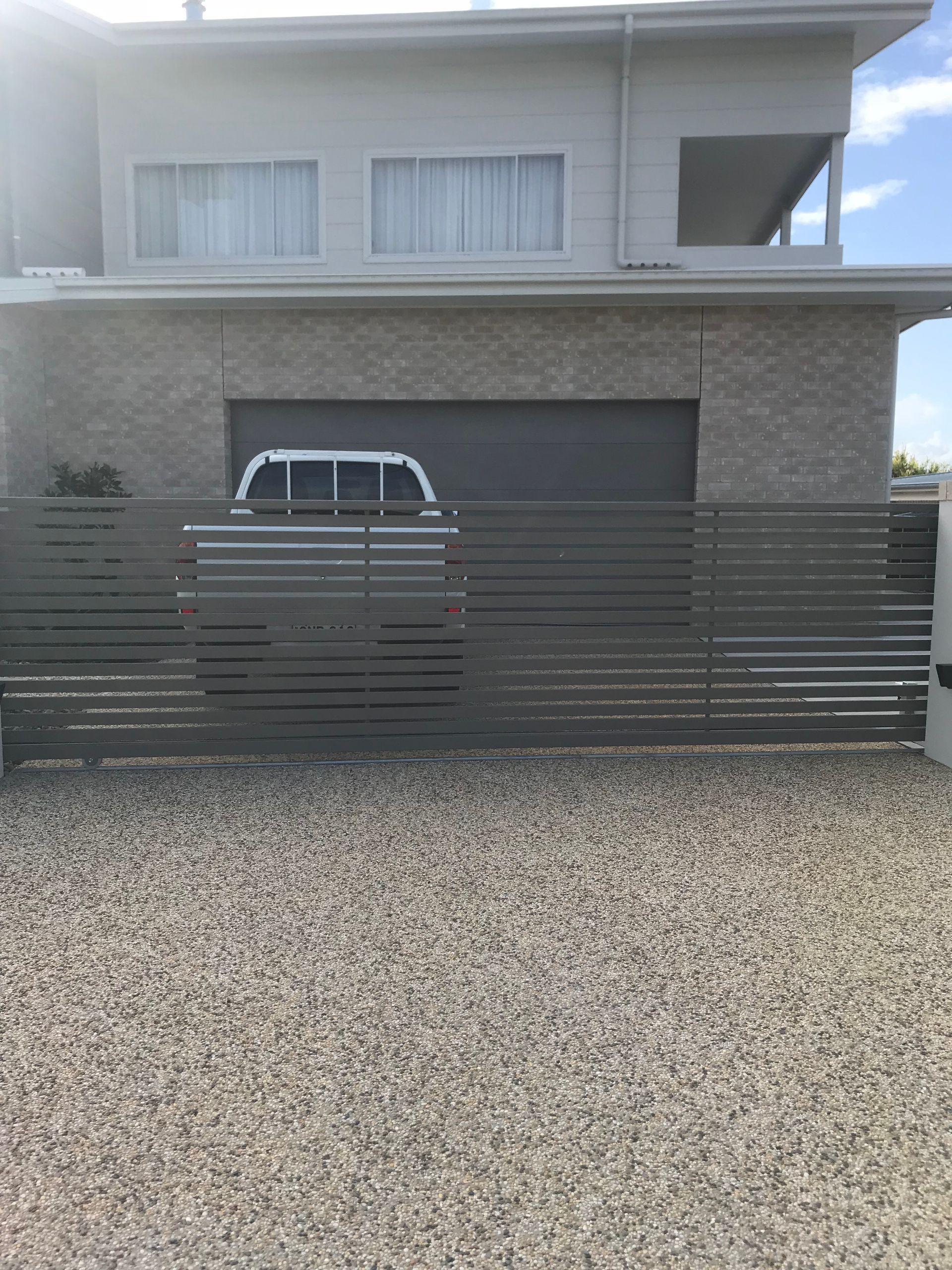 A white truck is parked in front of a large house behind a fence. — Fabricator In Coffs Harbour, NSW
