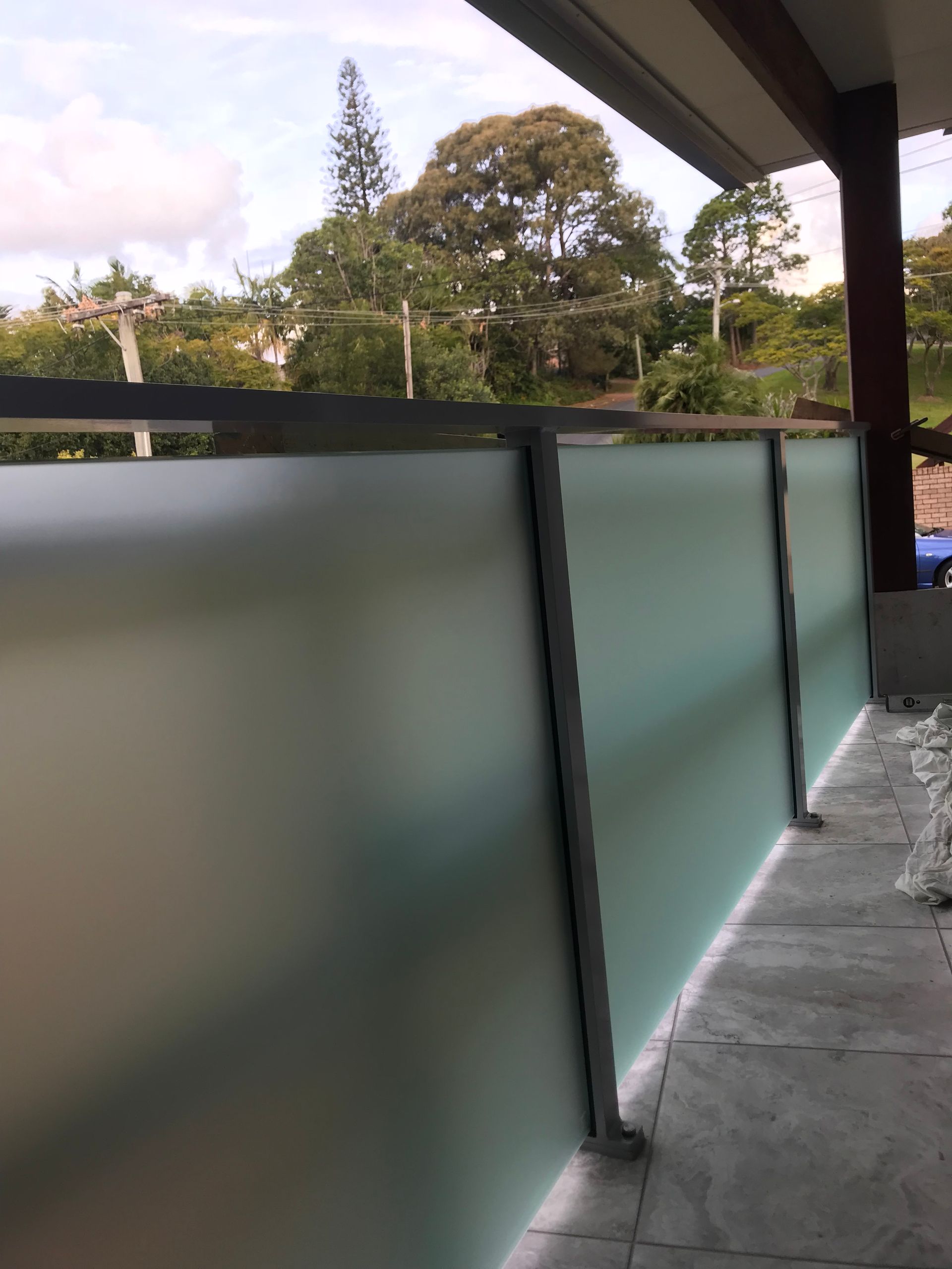 A balcony with a frosted glass fence and trees in the background — Fabricator In Coffs Harbour, NSW