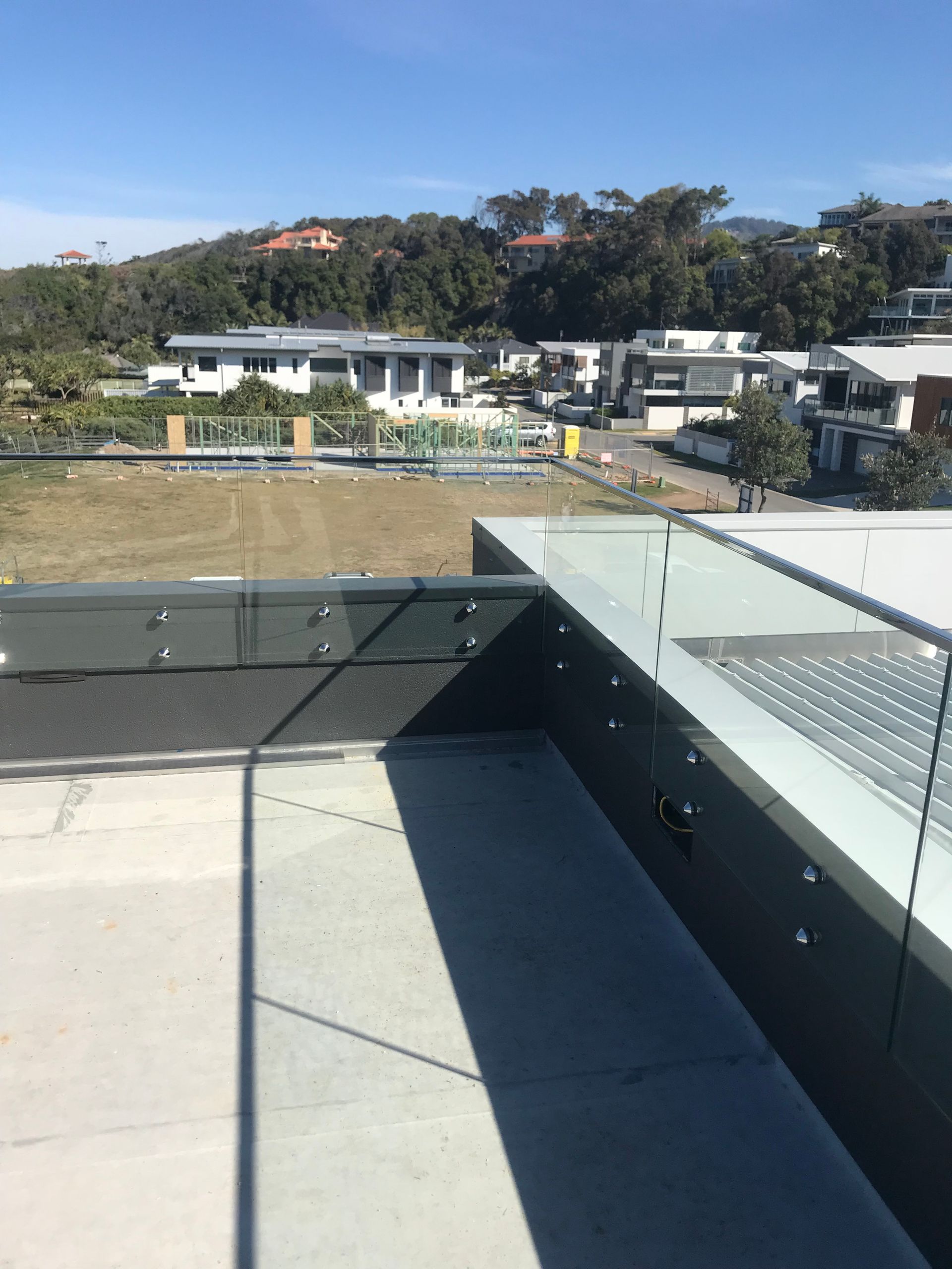 A balcony with a glass railing and a view of a city — Fabricator In Coffs Harbour, NSW