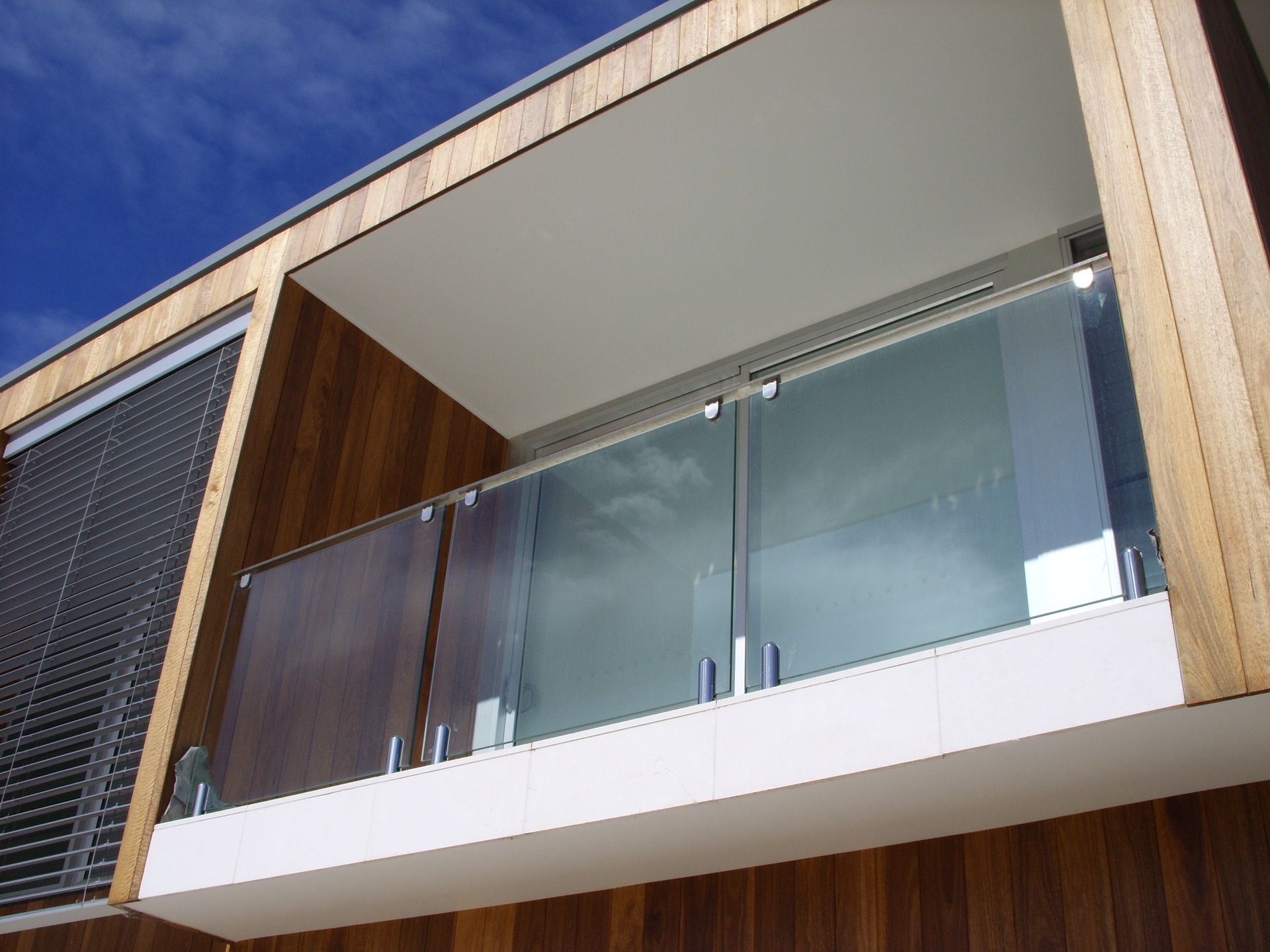A balcony with a glass railing on the side of a building — Fabricator In Coffs Harbour, NSW