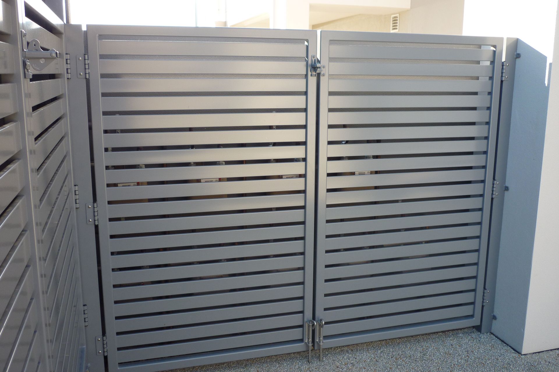 A gray metal gate is sitting next to a white wall — Fabricator In Coffs Harbour, NSW