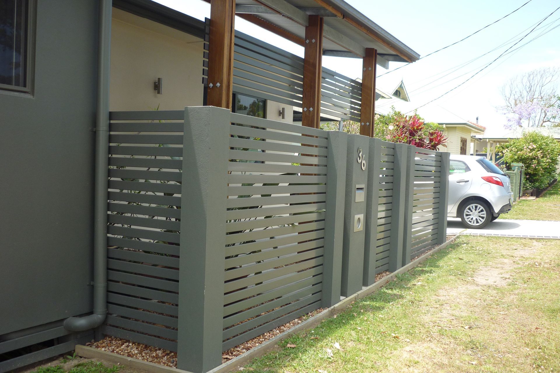 A car is parked behind a fence next to a house — Fabricator In Coffs Harbour, NSW