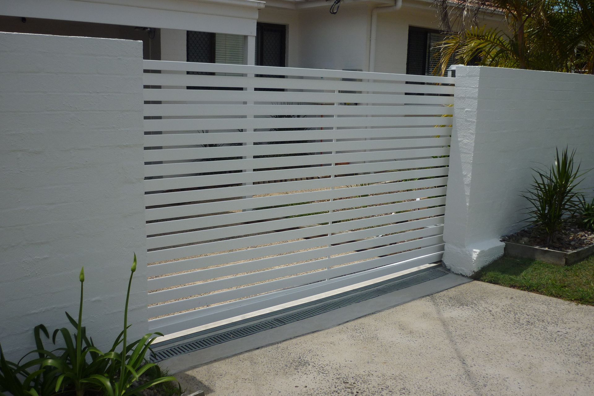 A white fence with a sliding gate in front of a house — Fabricator In Coffs Harbour, NSW