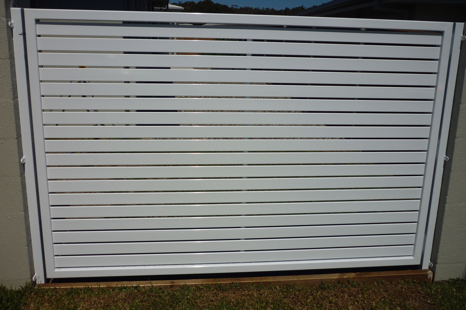 A white fence is sitting on top of a lush green field — Fabricator In Coffs Harbour, NSW