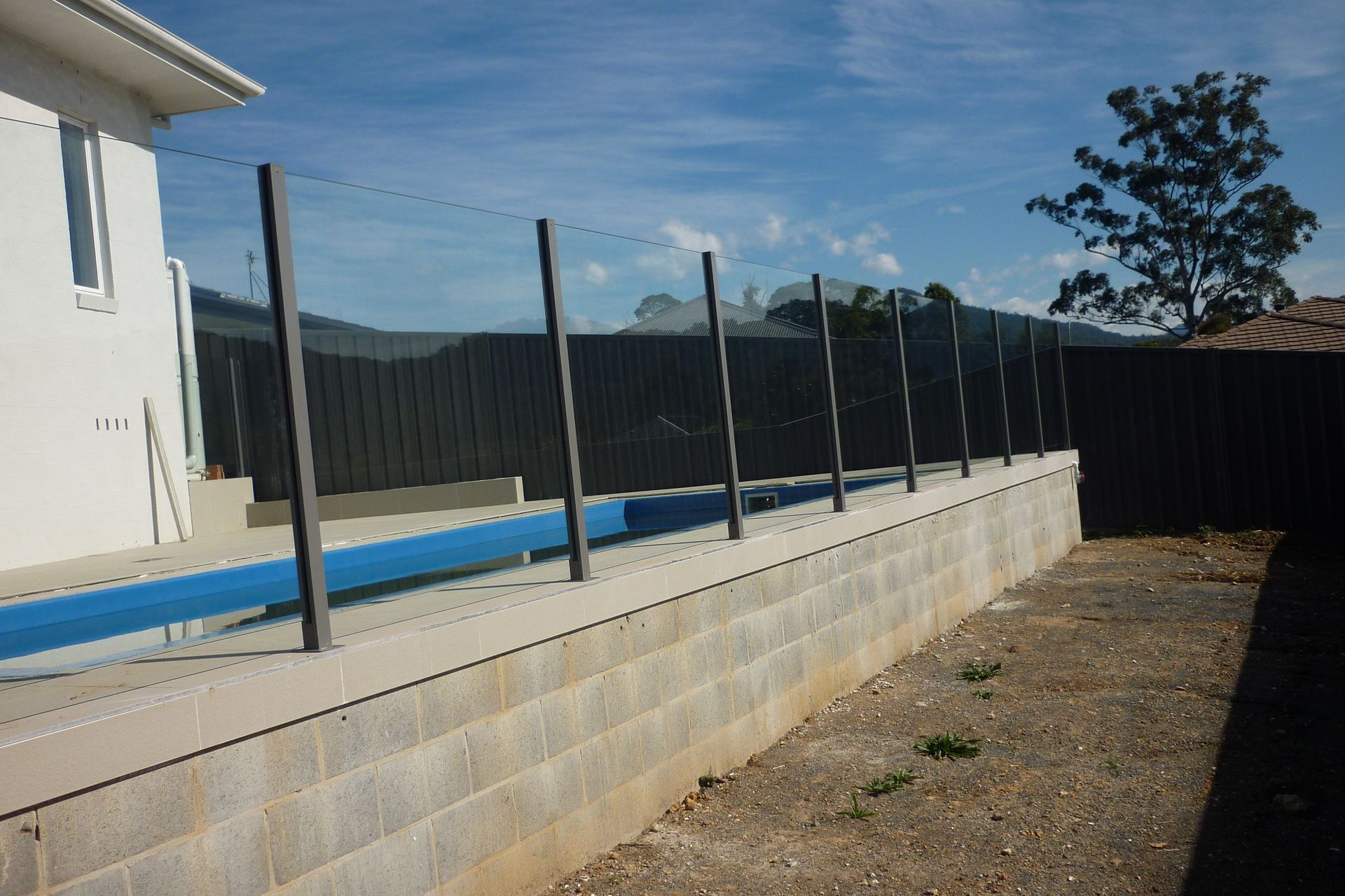 A fence surrounds a swimming pool in a backyard — Fabricator In Coffs Harbour, NSW