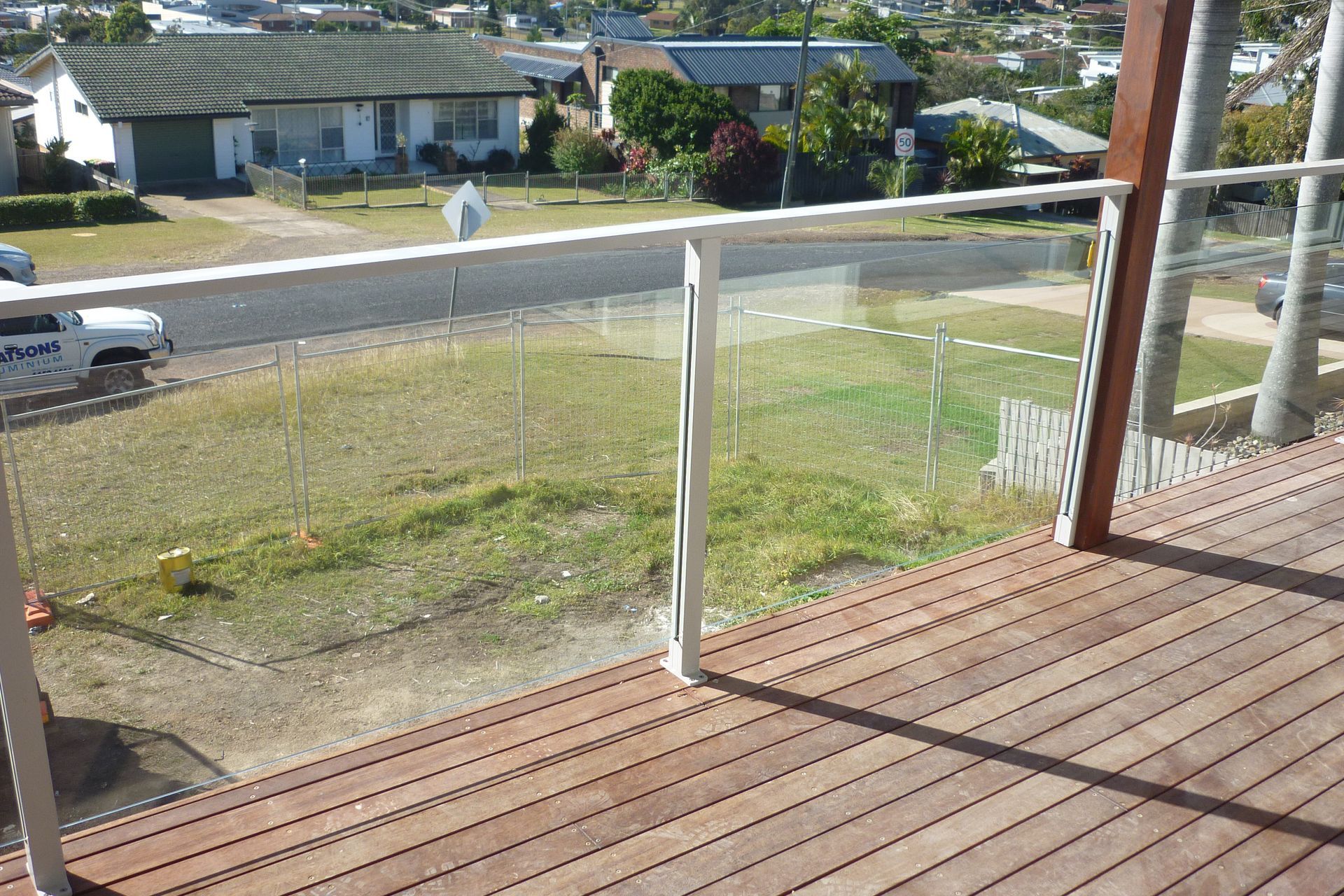 A wooden deck with a glass railing overlooking a residential area — Fabricator In Coffs Harbour, NSW