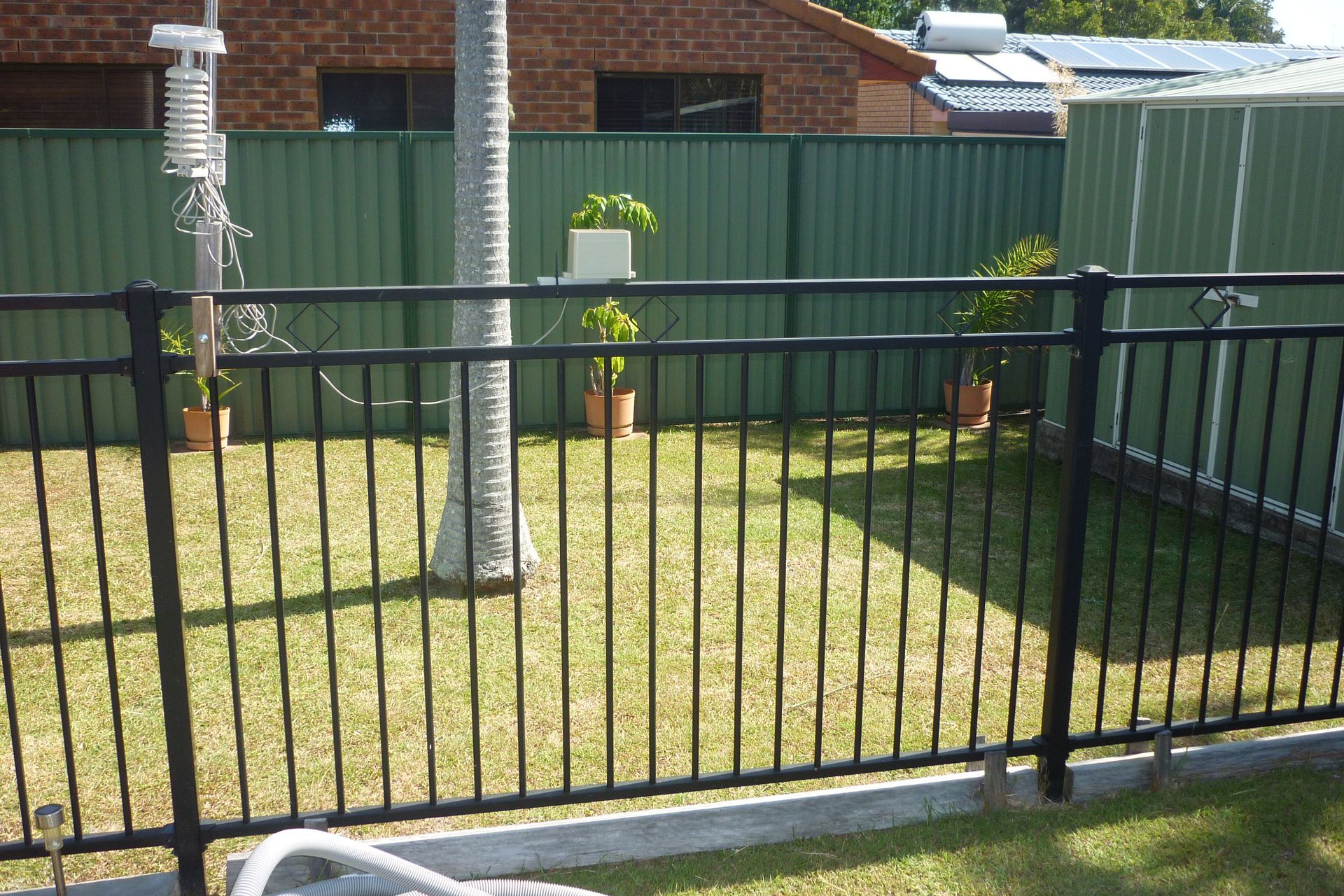 A black fence with a green fence behind it — Fabricator In Coffs Harbour, NSW