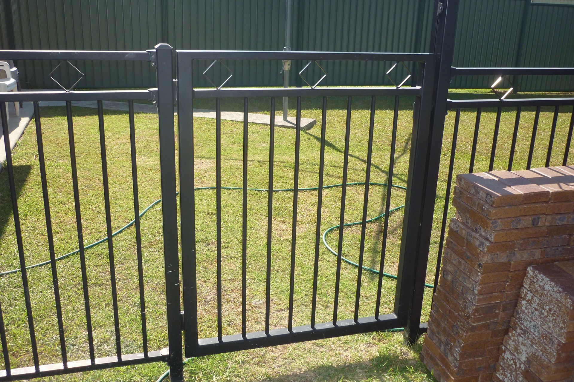 A black metal fence surrounds a lush green yard — Fabricator In Coffs Harbour, NSW