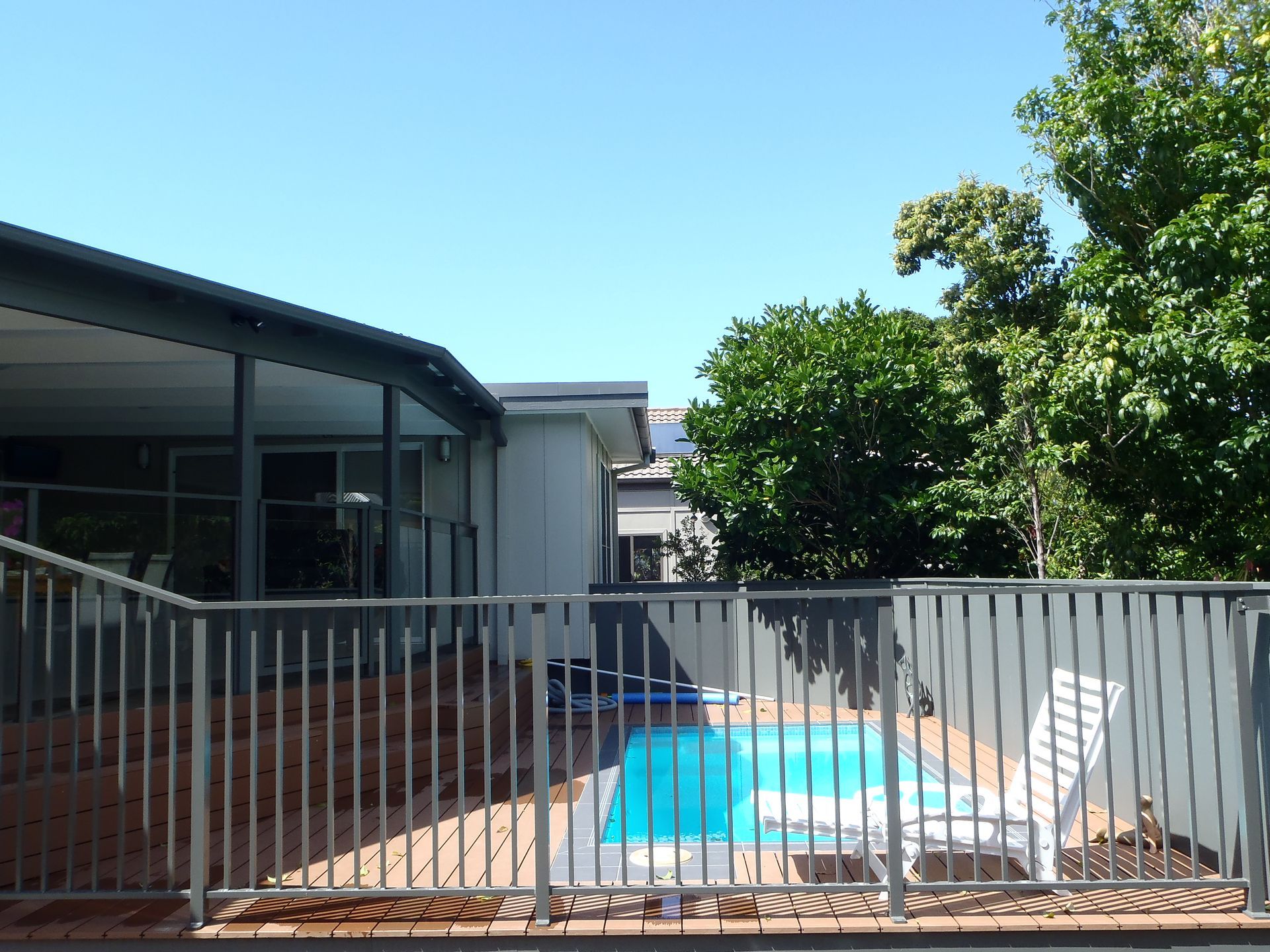 A fence surrounds a swimming pool in front of a house — Fabricator In Coffs Harbour, NSW
