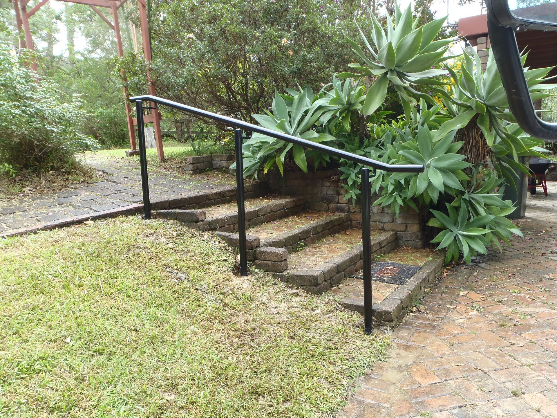 A black railing surrounds a set of stairs in a garden — Fabricator In Coffs Harbour, NSW