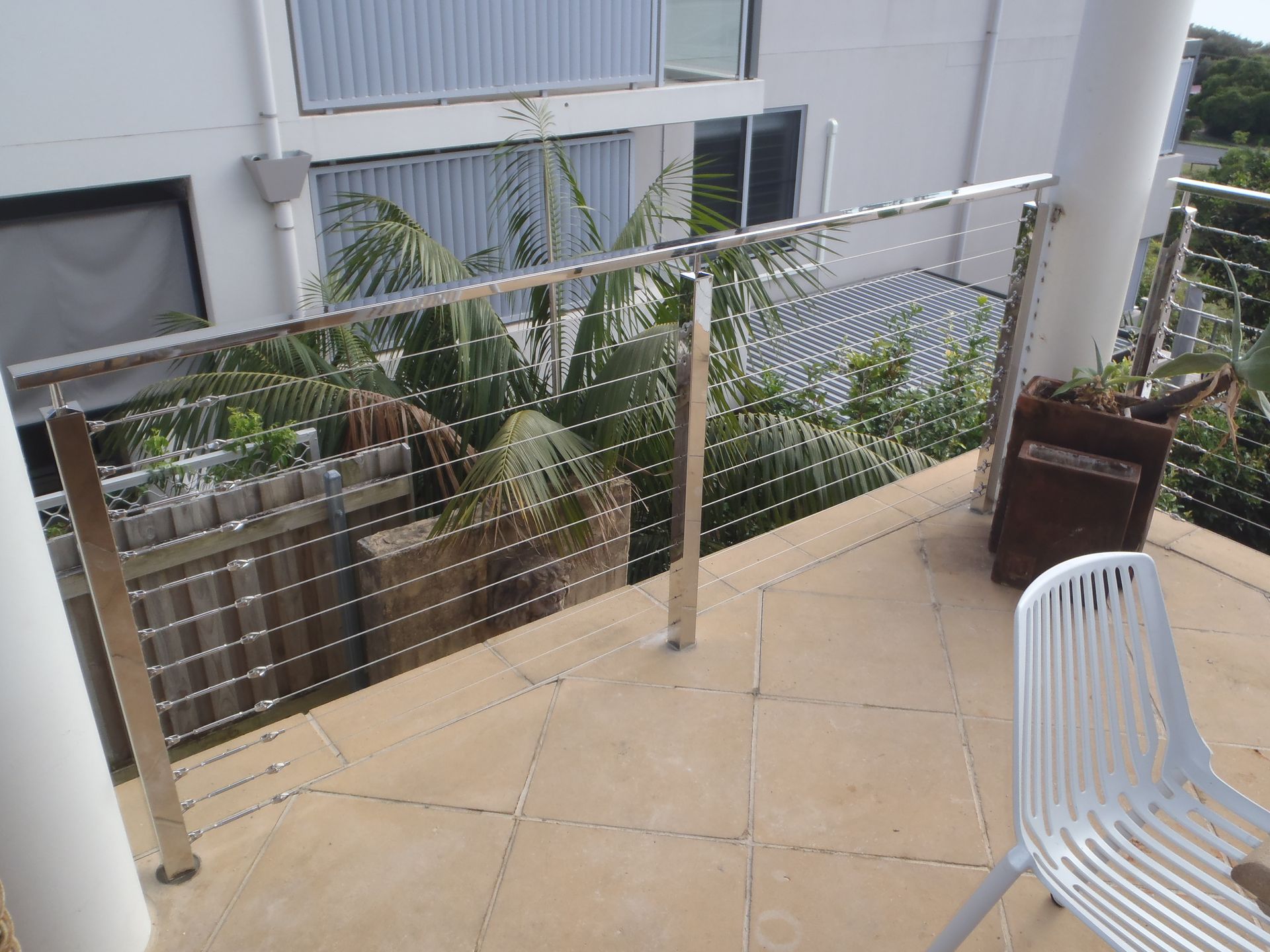 A balcony with a stainless steel railing and a chair — Fabricator In Coffs Harbour, NSW