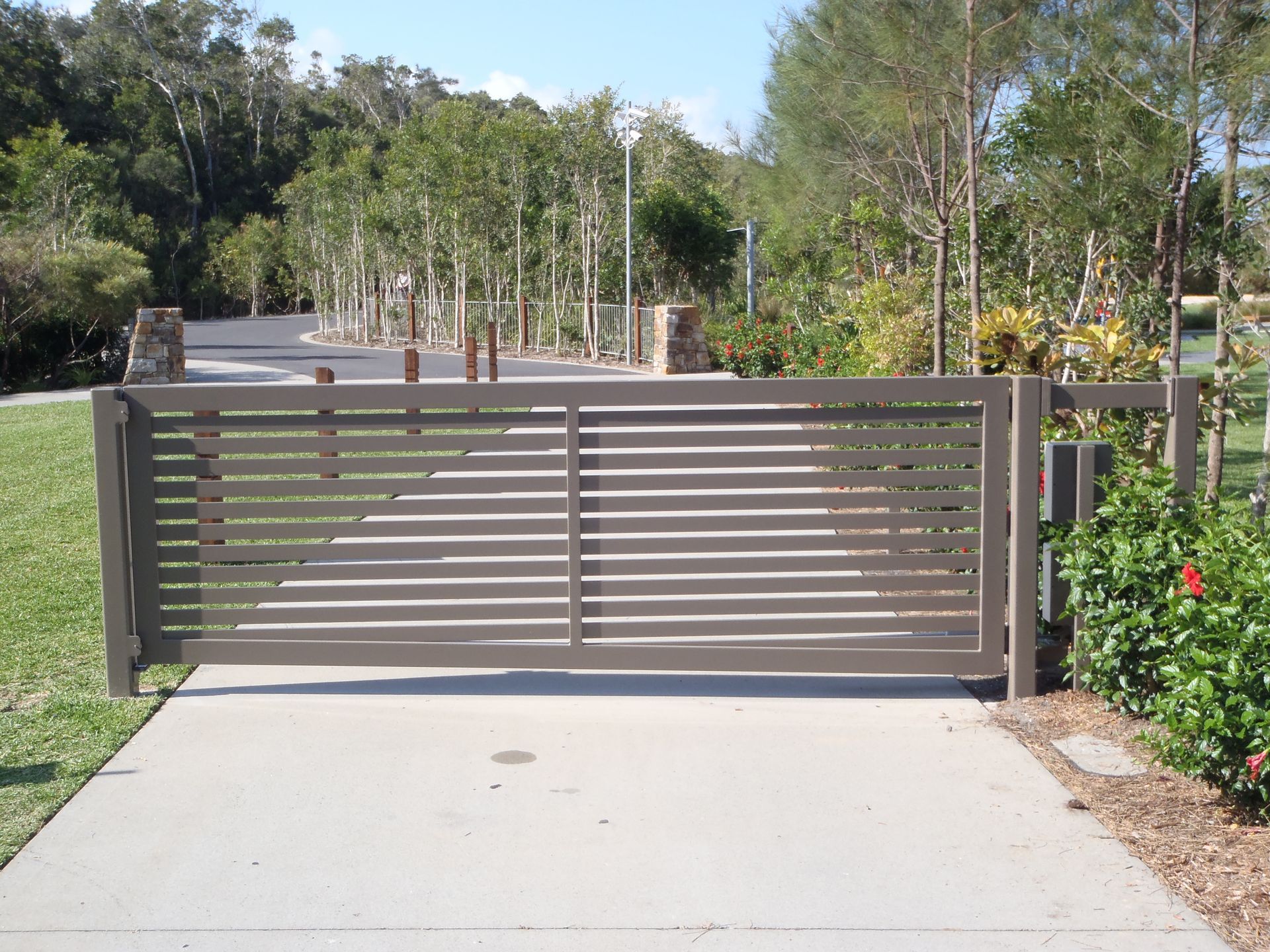 A sliding gate is open to a driveway with trees in the background — Fabricator In Coffs Harbour, NSW