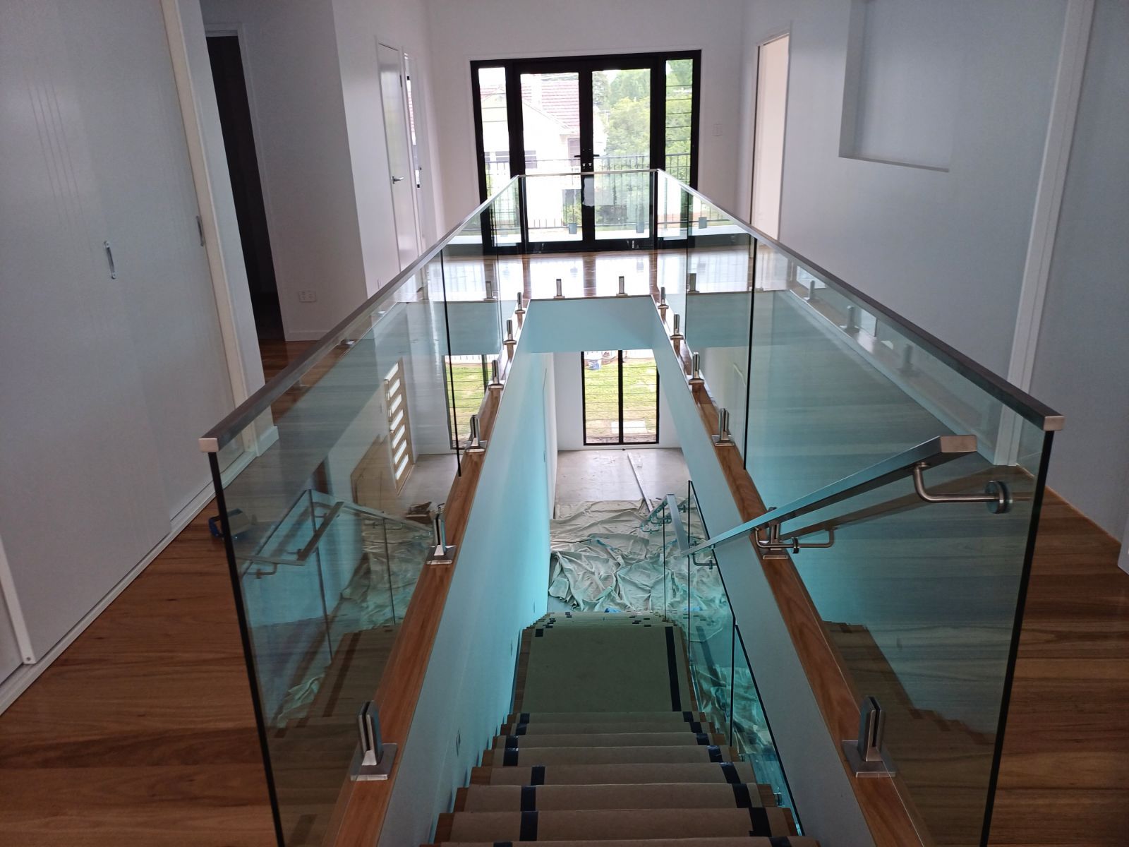 A staircase with a glass railing leading up to the second floor of a house — Fabricator In Coffs Harbour, NSW