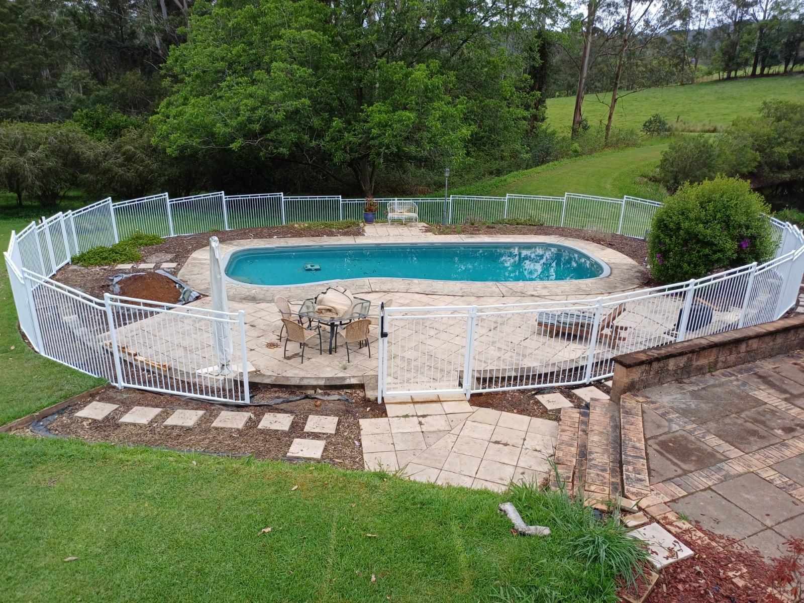 A large swimming pool is surrounded by a white fence — Fabricator In Coffs Harbour, NSW