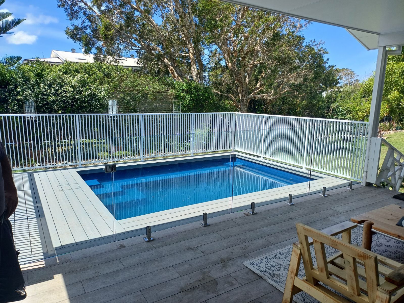 A large swimming pool is surrounded by a white fence and a wooden deck — Fabricator In Coffs Harbour, NSW