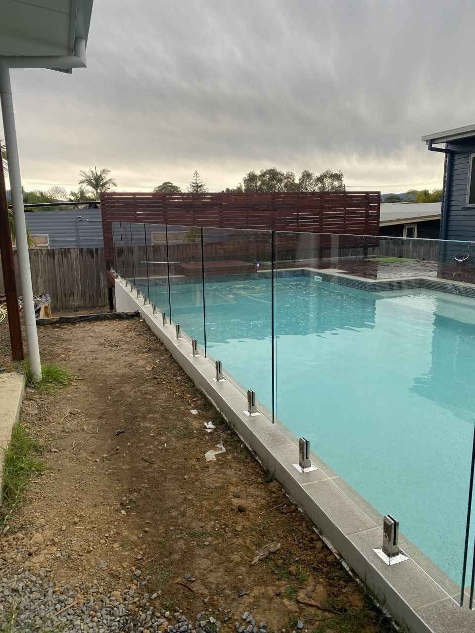 A swimming pool with a fence around it and a house in the background — Fabricator In Coffs Harbour, NSW