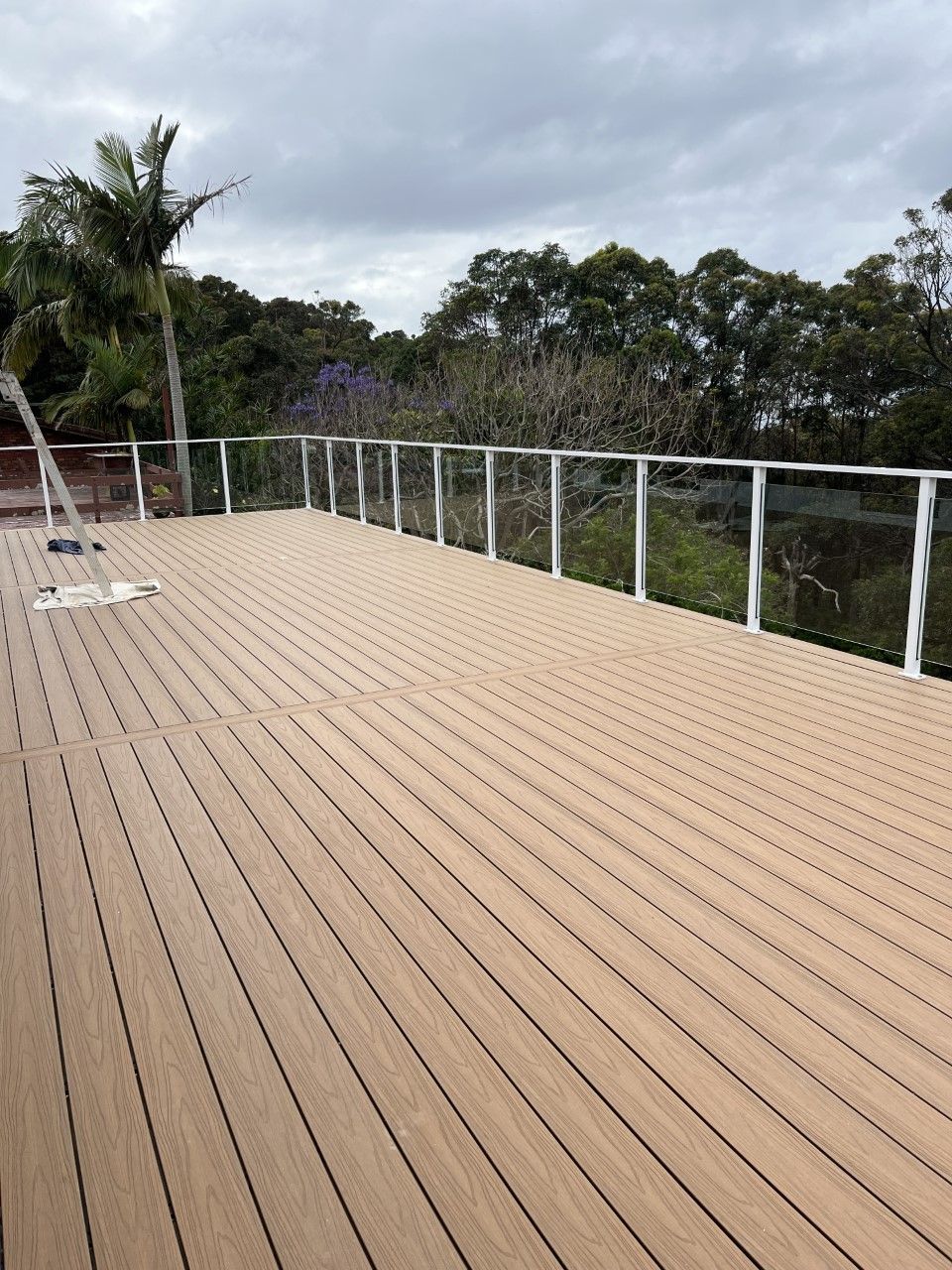 A wooden deck with a white railing and trees in the background — Fabricator In Coffs Harbour, NSW