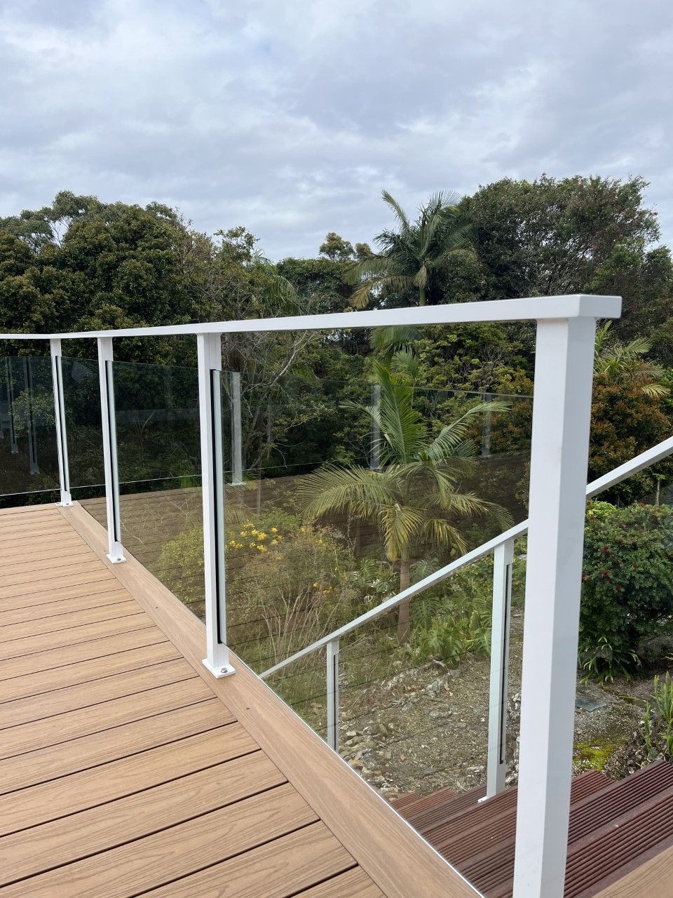 A wooden deck with a glass railing and stairs leading up to it — Fabricator In Coffs Harbour, NSW
