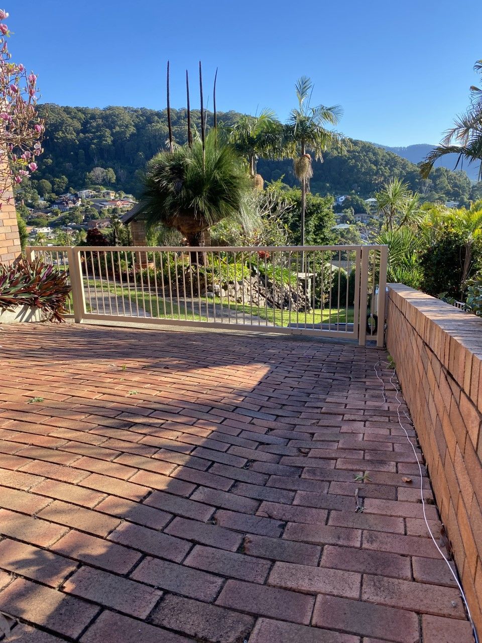 A brick walkway leading to a gate with a view of a lush green hillside — Fabricator In Coffs Harbour, NSW