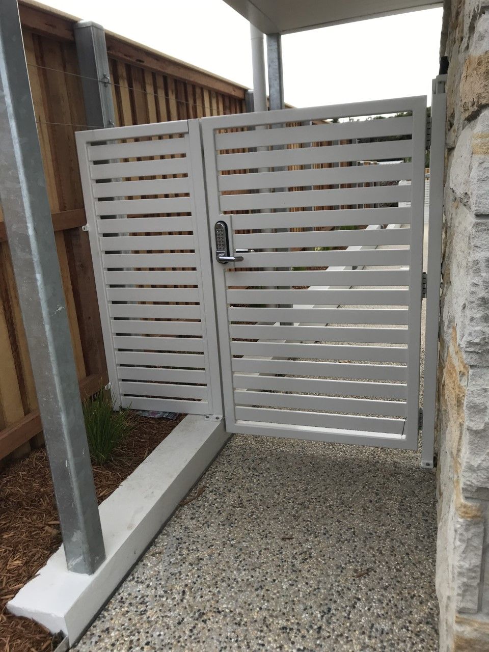 A white gate with a metal post and a wooden fence behind it — Fabricator In Coffs Harbour, NSW