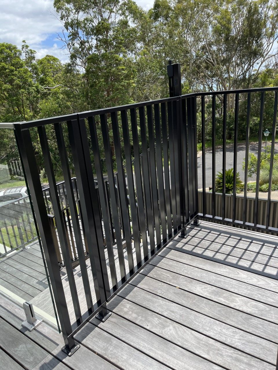 A black railing on a wooden deck with trees in the background — Fabricator In Coffs Harbour, NSW