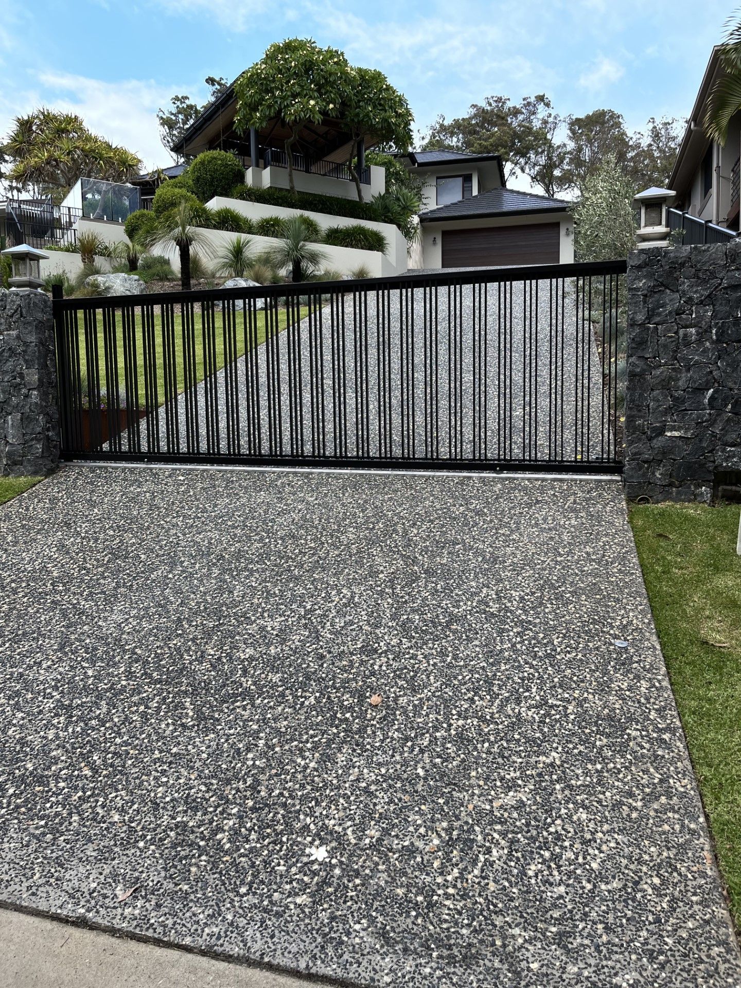 A concrete driveway with a sliding gate in front of a house — Fabricator In Coffs Harbour, NSW