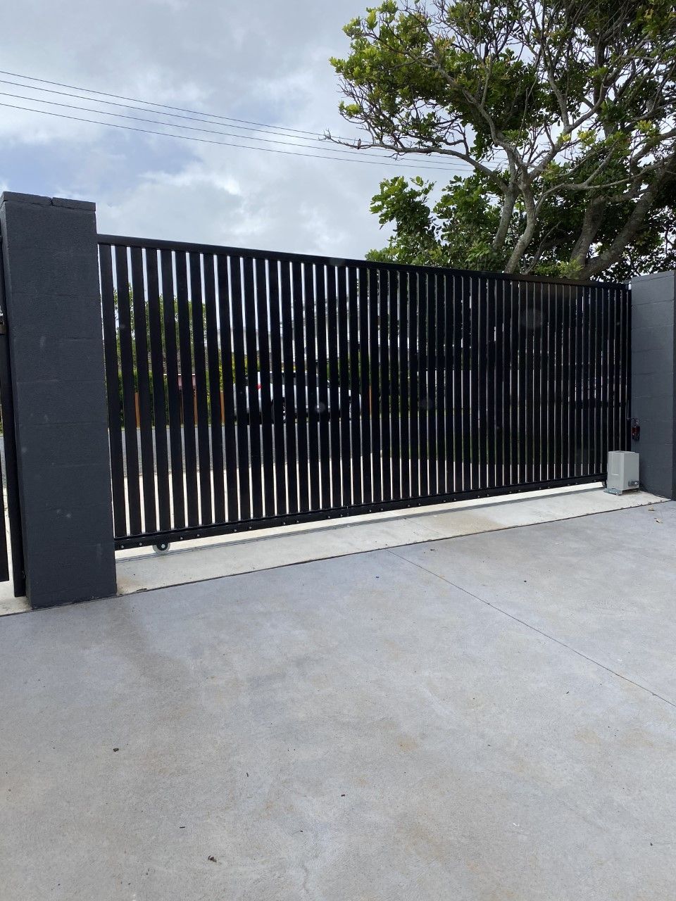 A black fence is sitting on top of a concrete driveway — Fabricator In Coffs Harbour, NSW