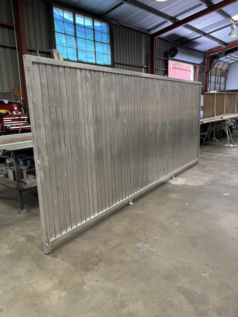 A large stainless steel gate is sitting in a warehouse — Fabricator In Coffs Harbour, NSW