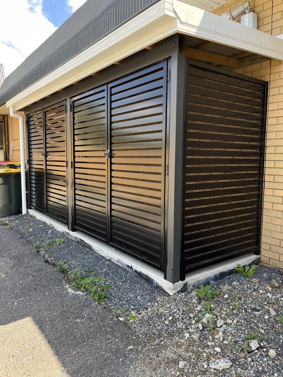 A black fence is sitting next to a brick building — Fabricator In Coffs Harbour, NSW