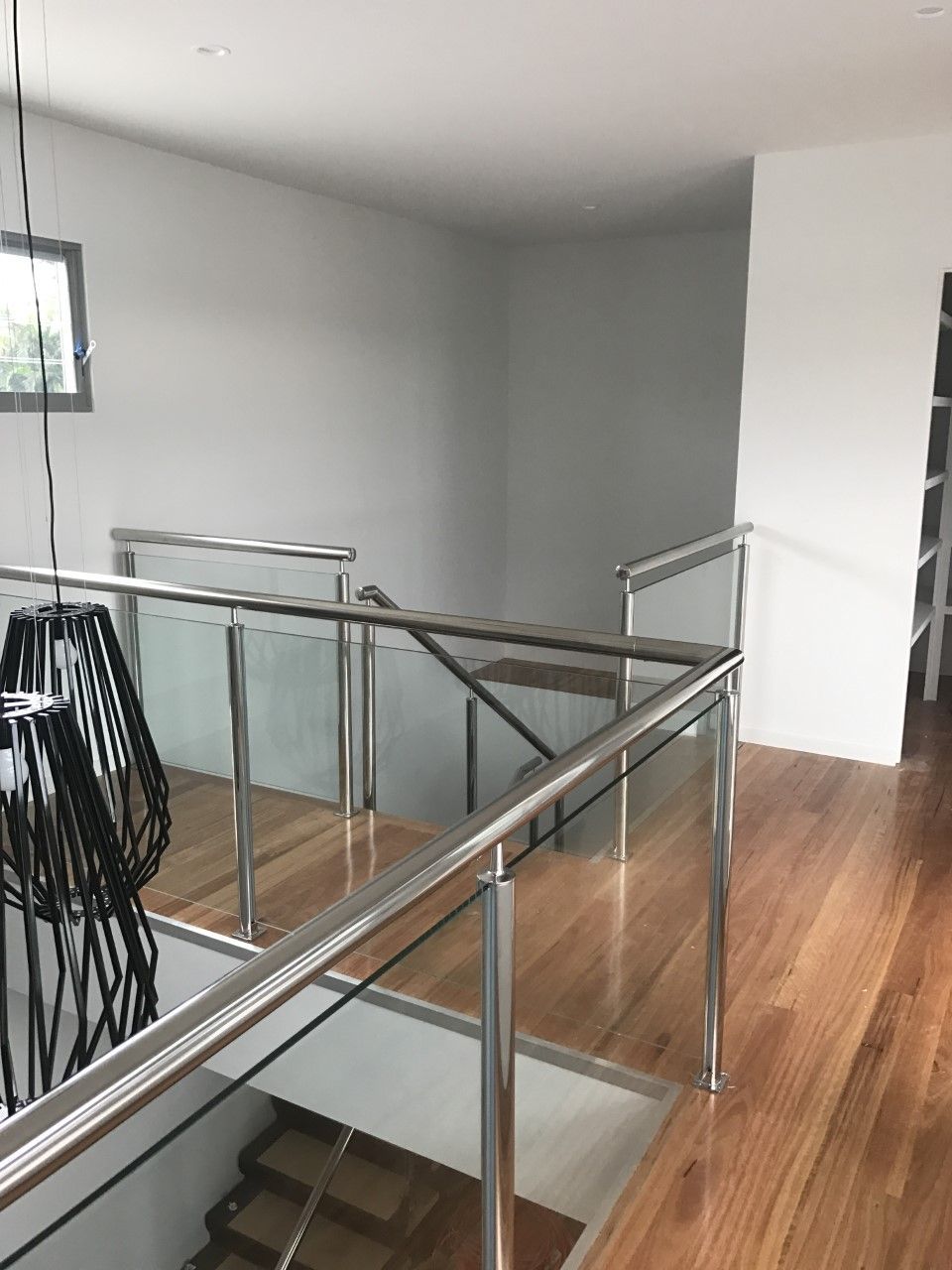 A staircase with a glass railing and wooden floors in a house — Fabricator In Coffs Harbour, NSW