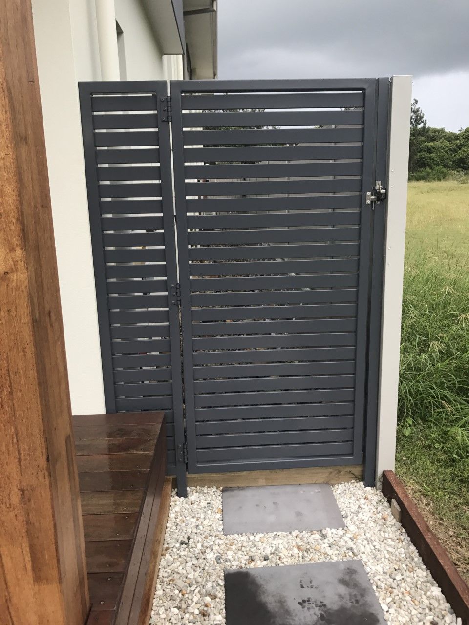A black gate is surrounded by gravel in front of a house — Fabricator In Coffs Harbour, NSW
