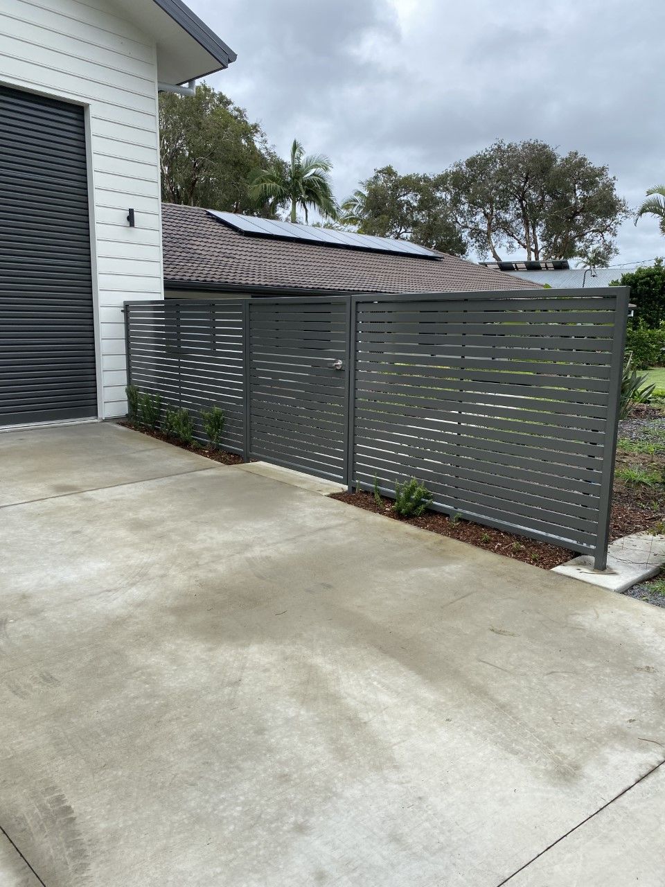 A fence is surrounding a driveway in front of a house — Fabricator In Coffs Harbour, NSW