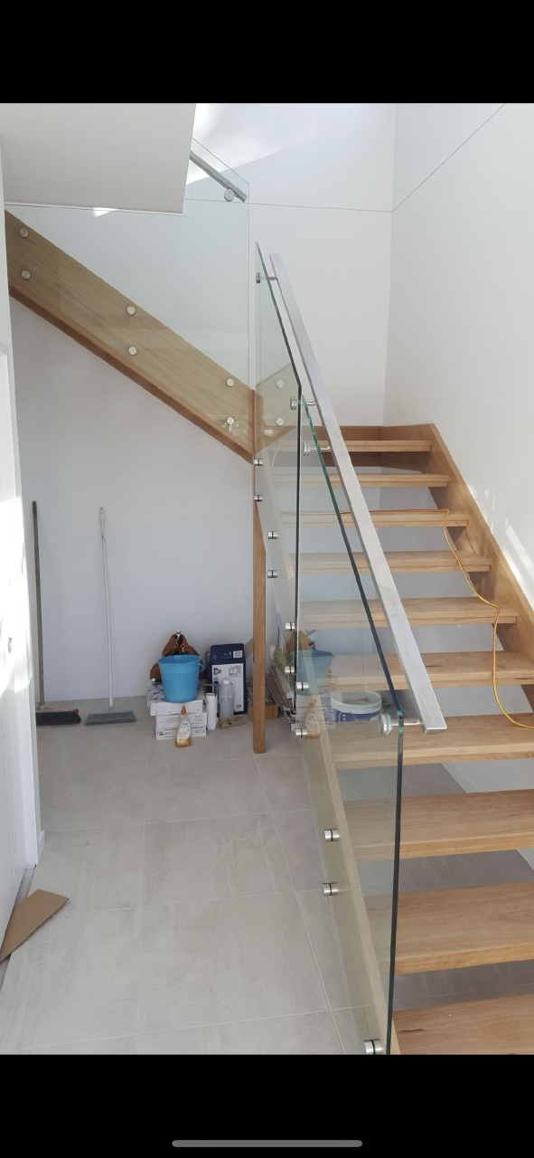 A wooden staircase with a glass railing in a room — Fabricator In Coffs Harbour, NSW