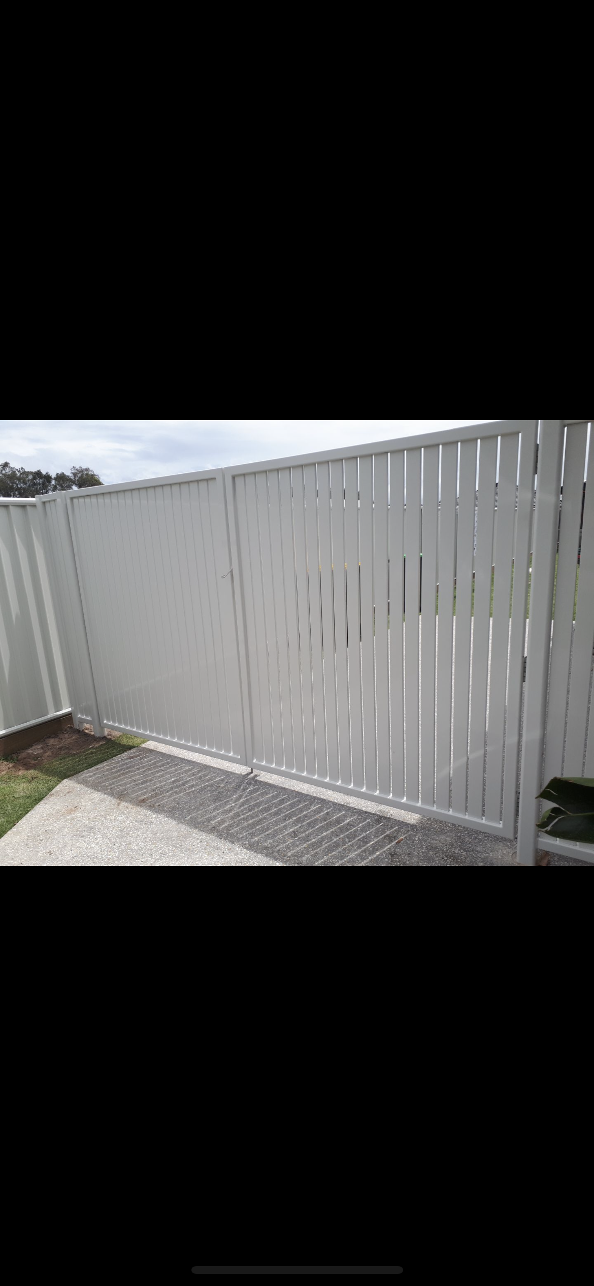 A white fence is sitting on top of a gravel driveway — Fabricator In Coffs Harbour, NSW