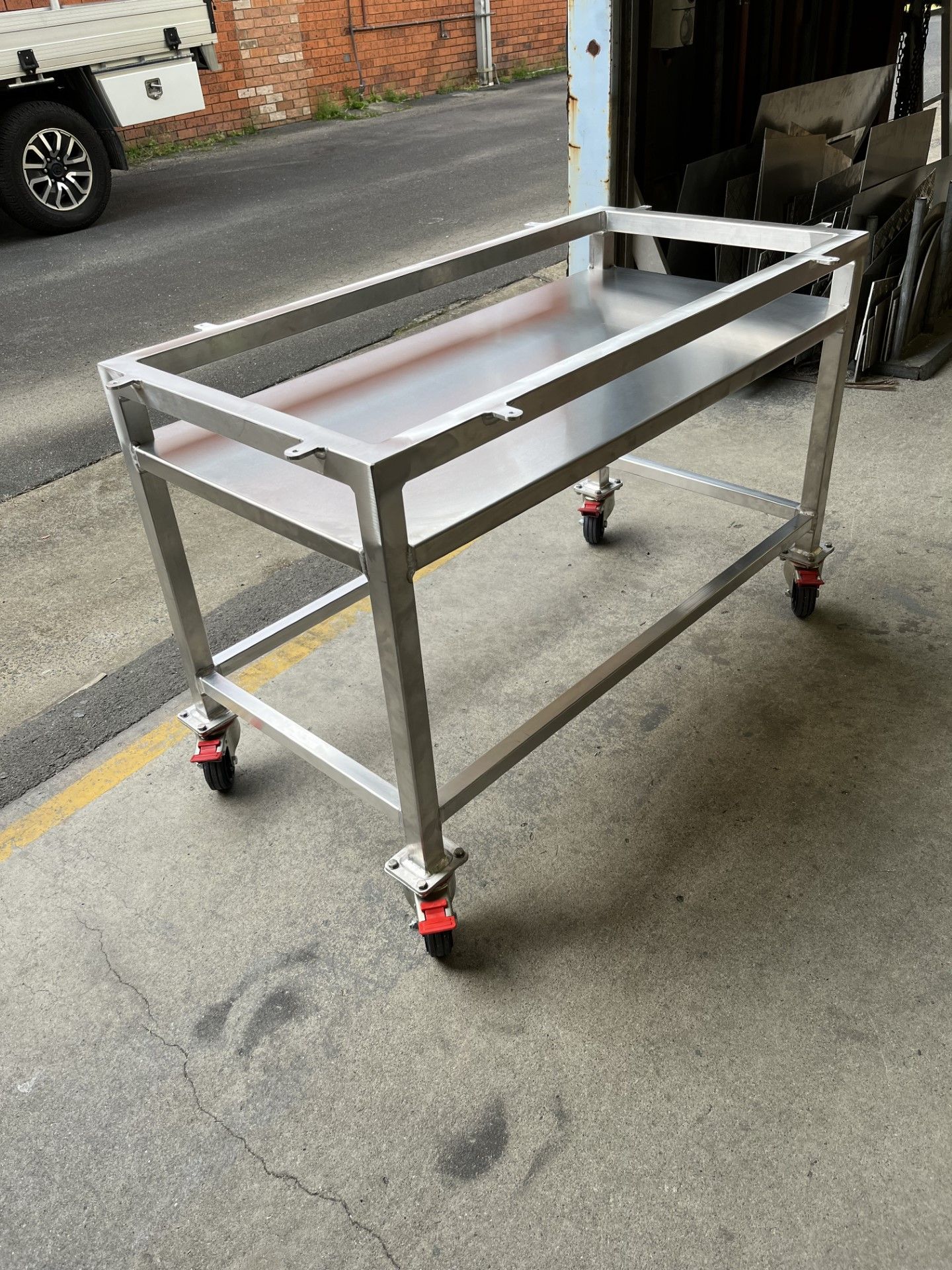 A stainless steel table with wheels is sitting on the side of the road — Fabricator In Coffs Harbour, NSW