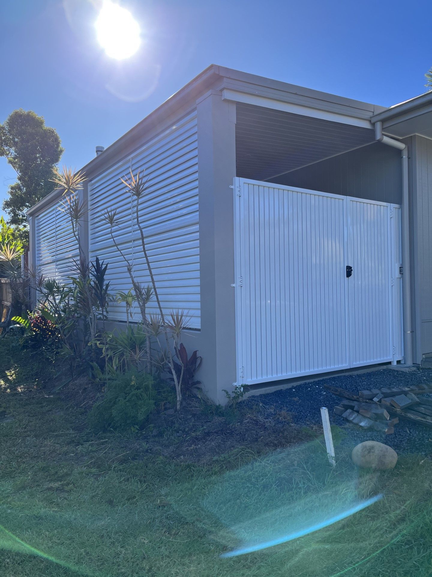 A white garage door is sitting in front of a house — Fabricator In Coffs Harbour, NSW