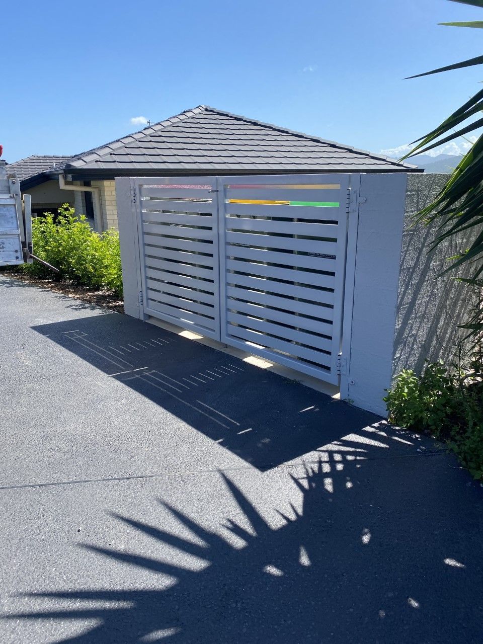 A white fence is sitting on the side of a road next to a house — Fabricator In Coffs Harbour, NSW