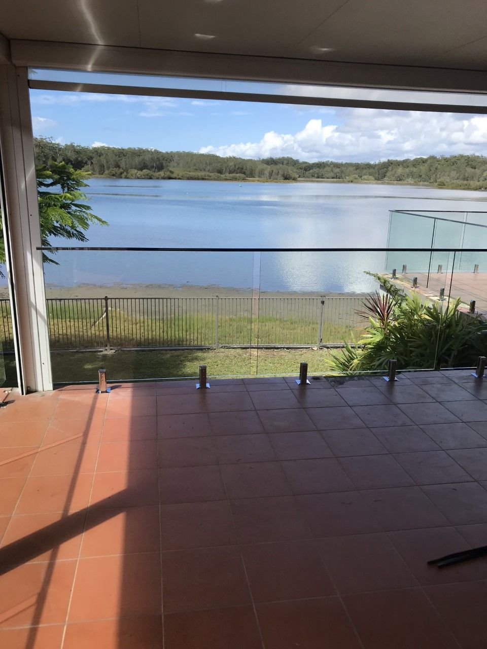 A balcony overlooking a lake with a glass railing — Fabricator In Coffs Harbour, NSW
