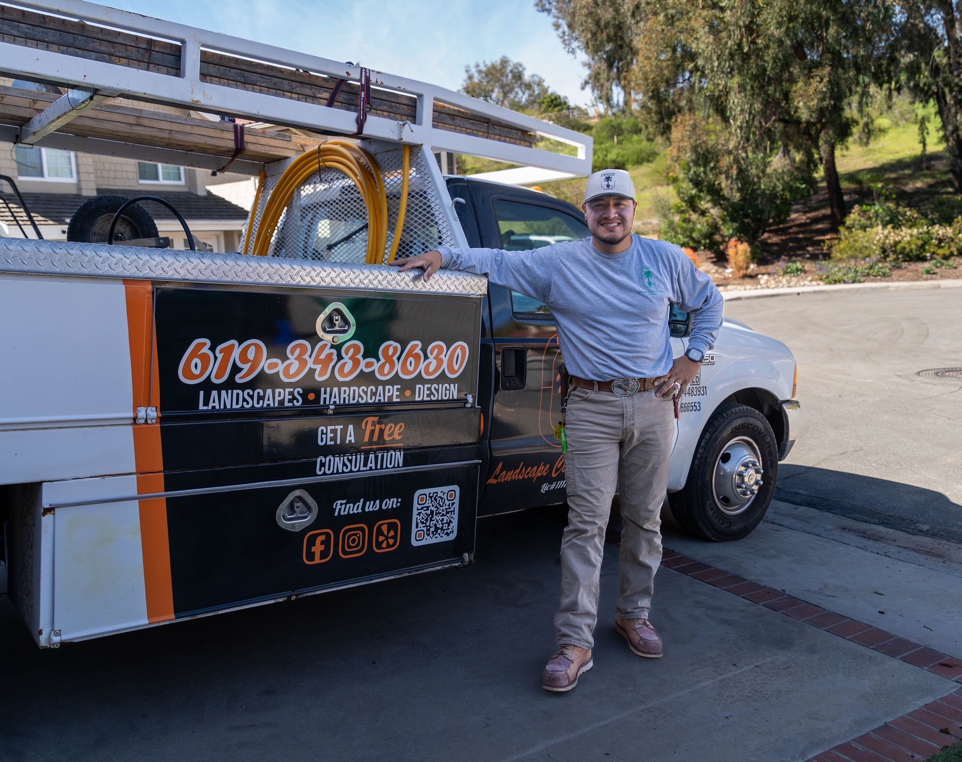 Three people in branded uniforms and caps stand with arms crossed in front of a work truck.